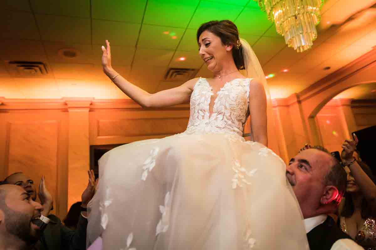 Bride held up on chair by guests at a Giando on the Water wedding