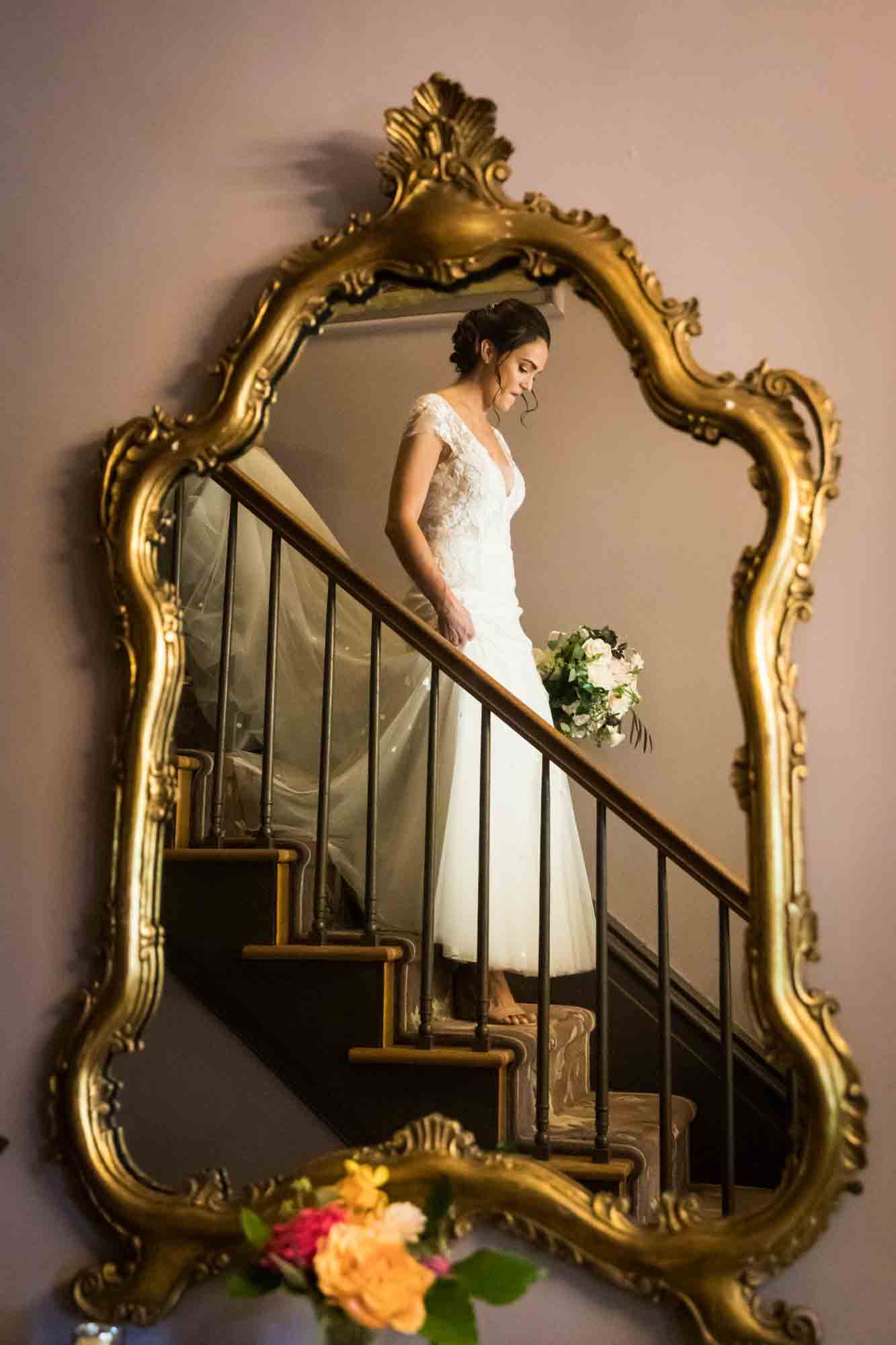 Reflection in gold framed mirror of bride coming down steps at a FEAST at Round Hill wedding