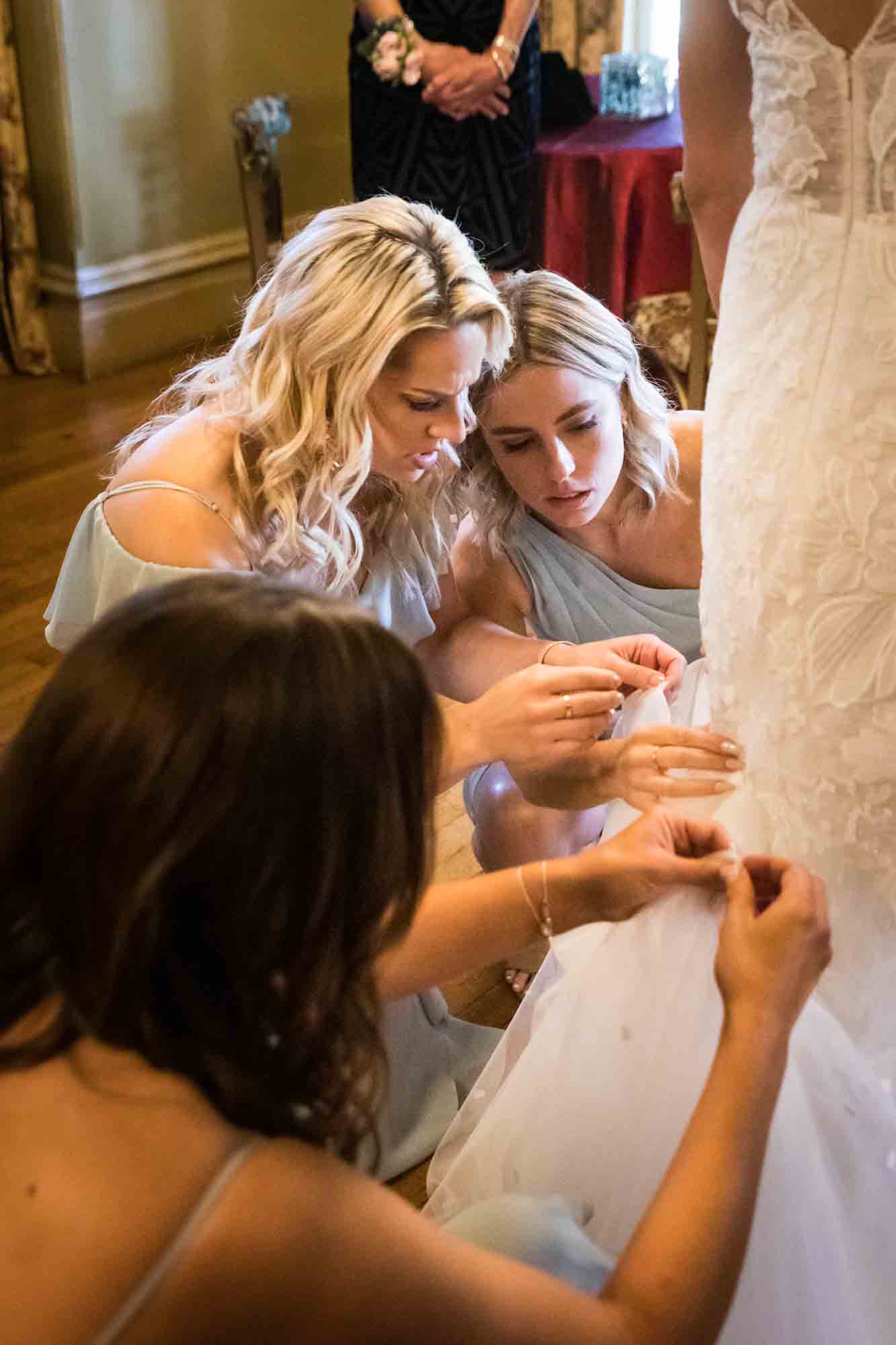 Bridesmaids helping to bustle bride's dress at a FEAST at Round Hill wedding