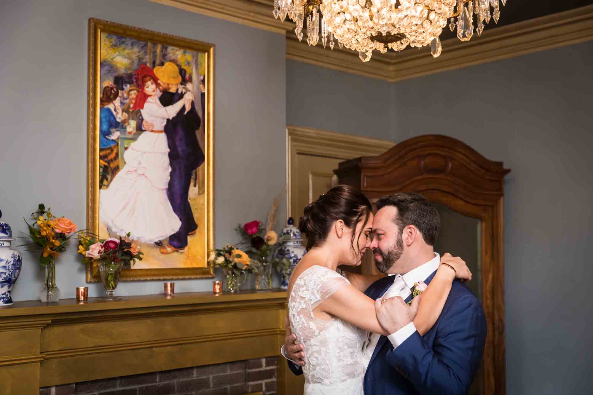 FEAST at Round Hill wedding photos of bride and groom hugging in front of painting