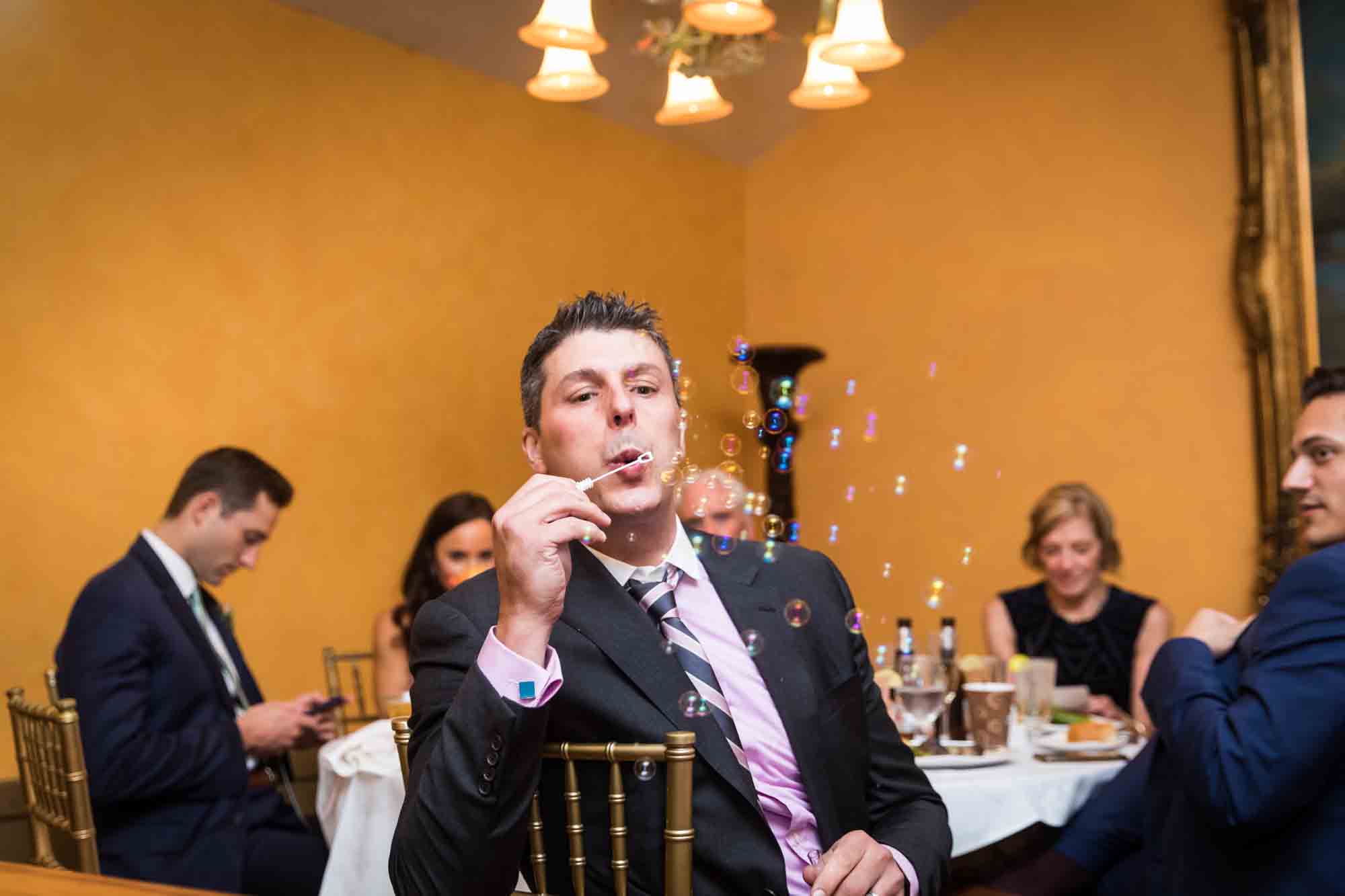 FEAST at Round Hill wedding photos of male guest blowing bubbles at camera