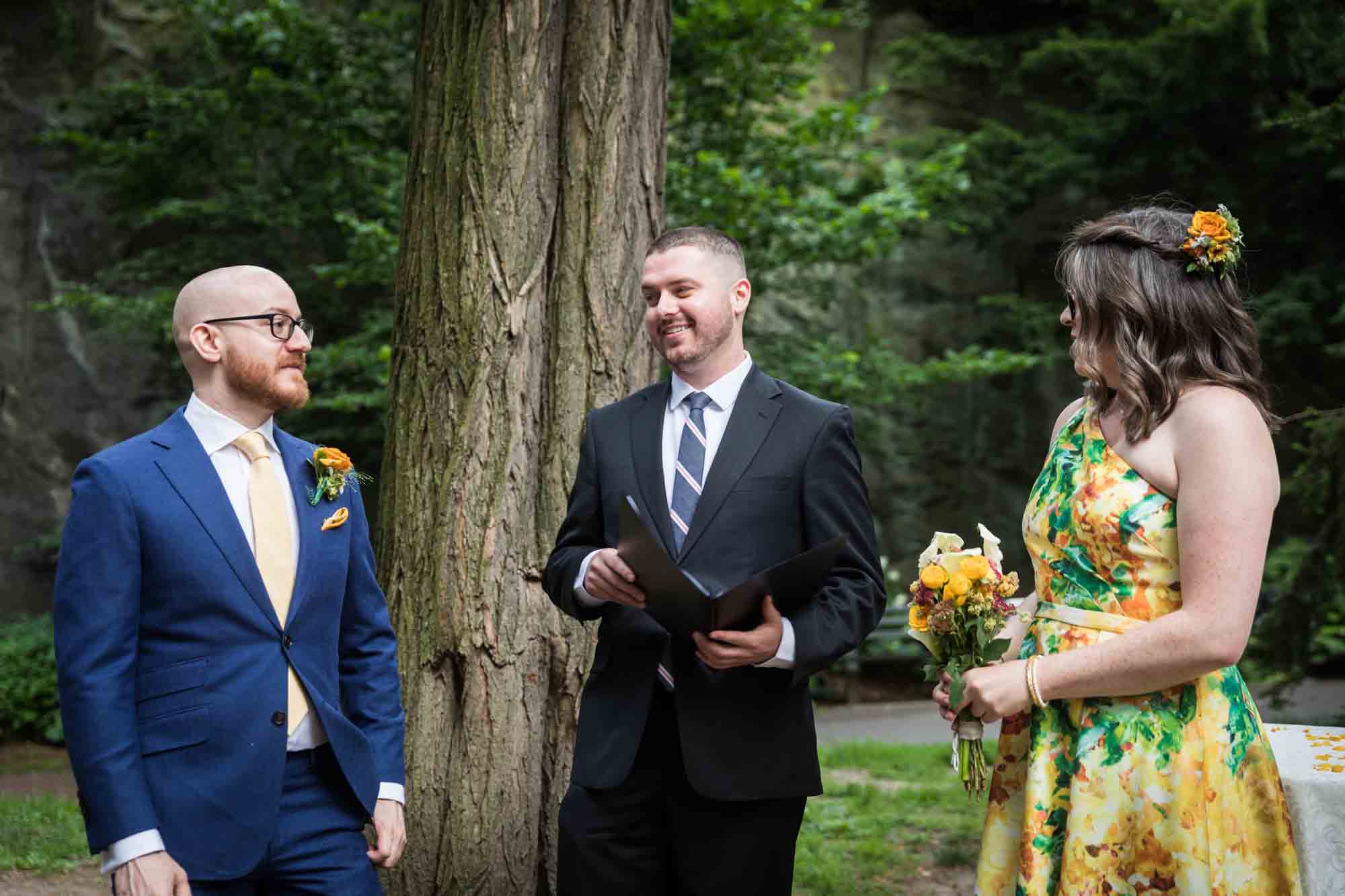 Bride and groom standing in front of officiant in garden for an article on how to select a wedding date