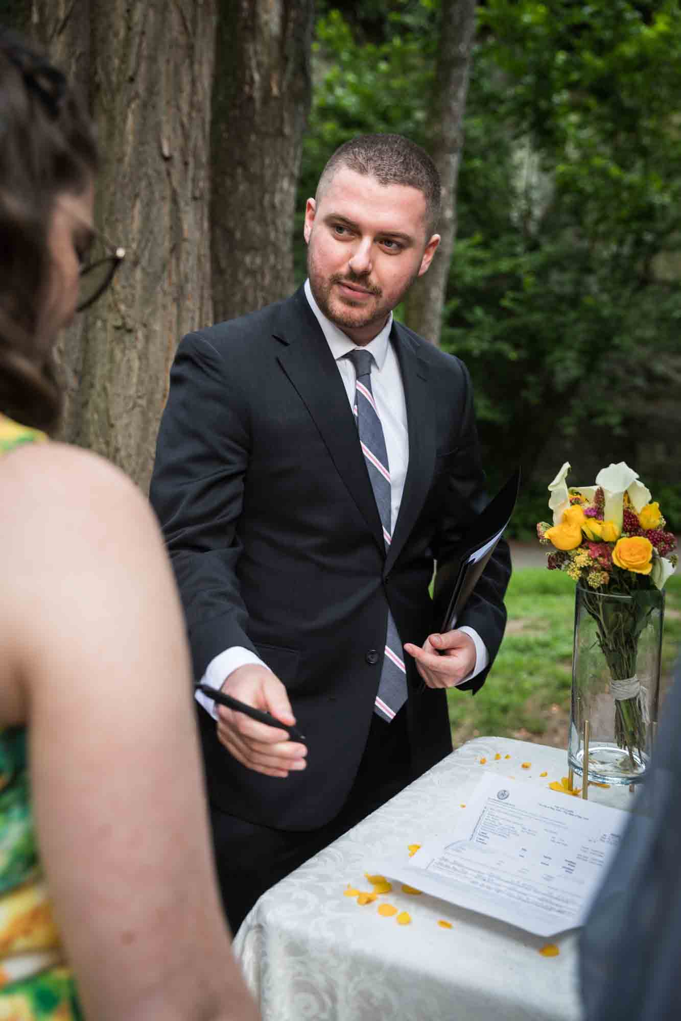 Officiant handing pen to bride for an article on how to select a wedding date