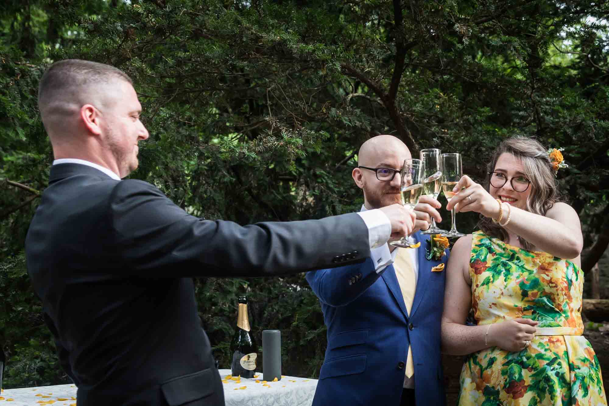 Officiant toasting champagne glass with bride and groom for an article on how to select a wedding date