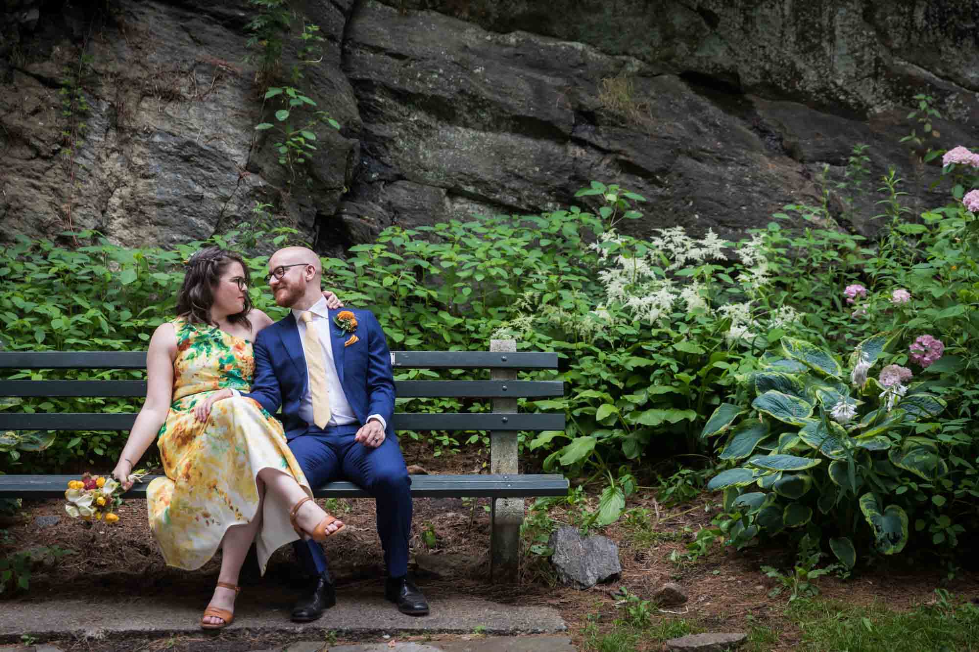 Bride and groom sitting on bench in garden for an article on how to select a wedding date