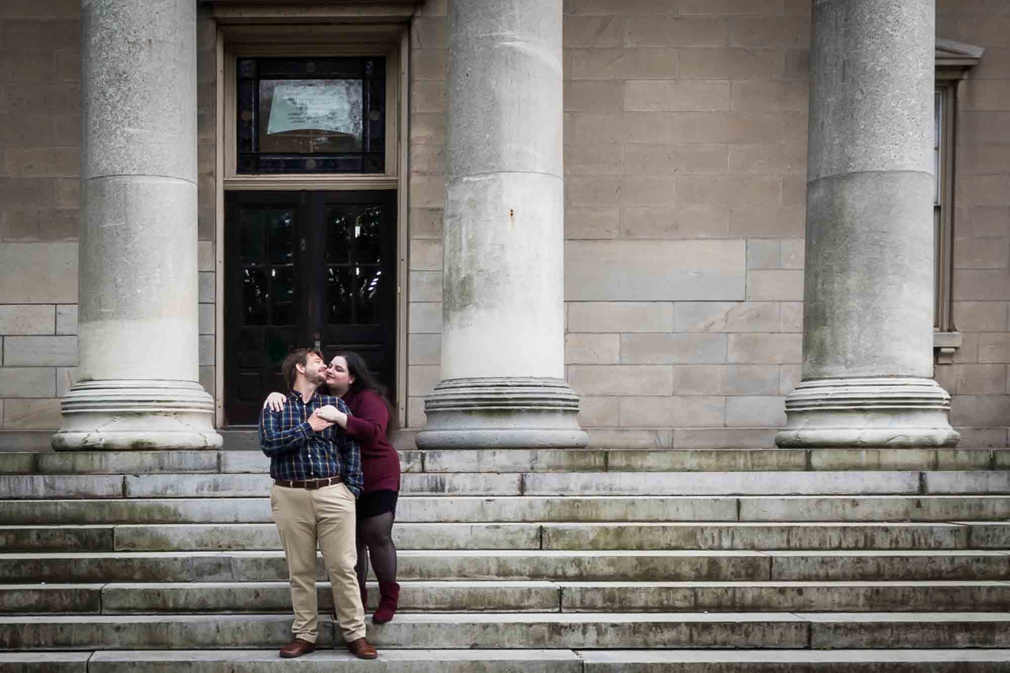 Snug Harbor engagement photos of couple hugging on steps of Newhouse Center for Contemporary Art