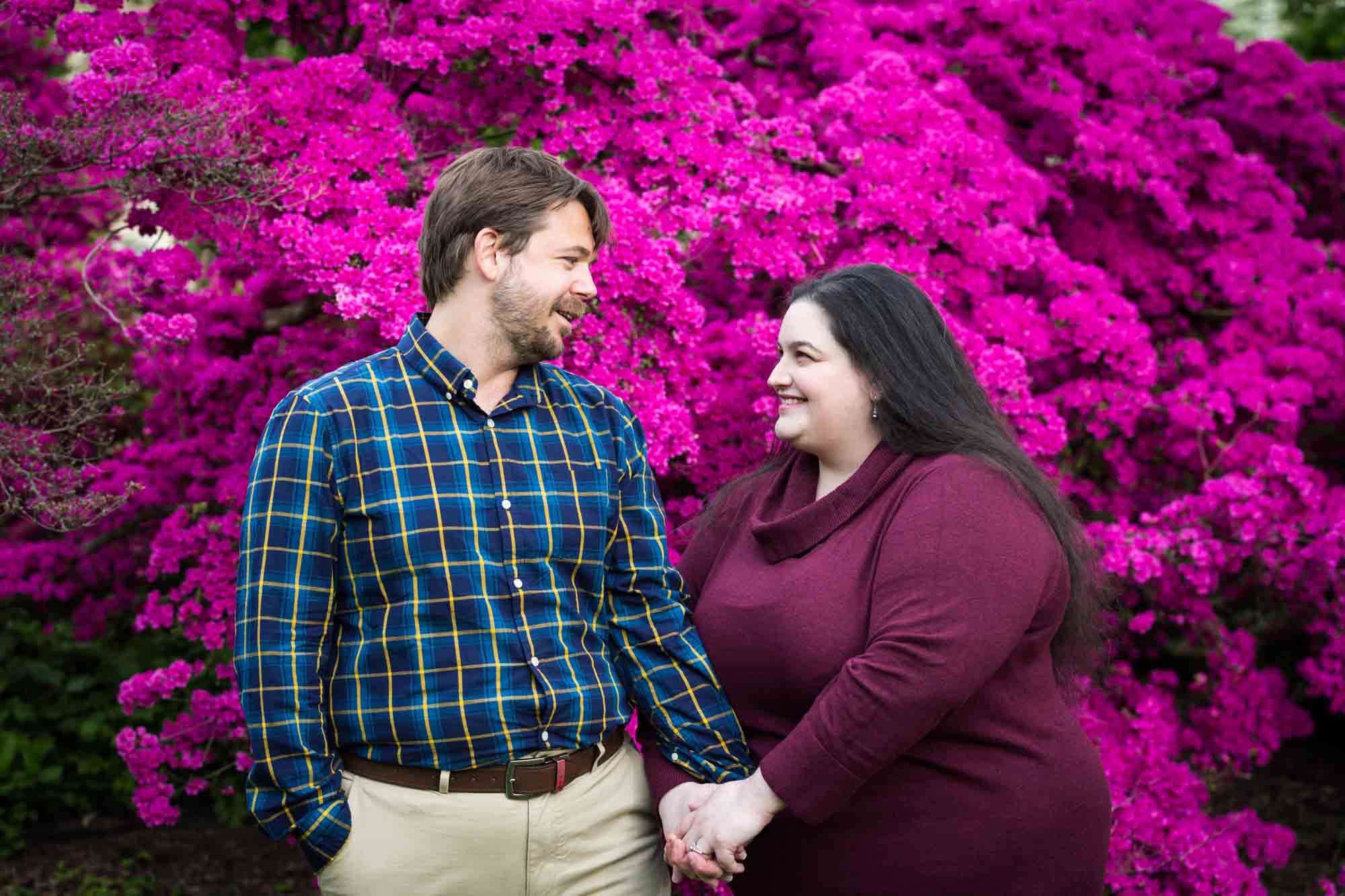 Snug Harbor engagement photos of couple holding hands in front of pink azaleas