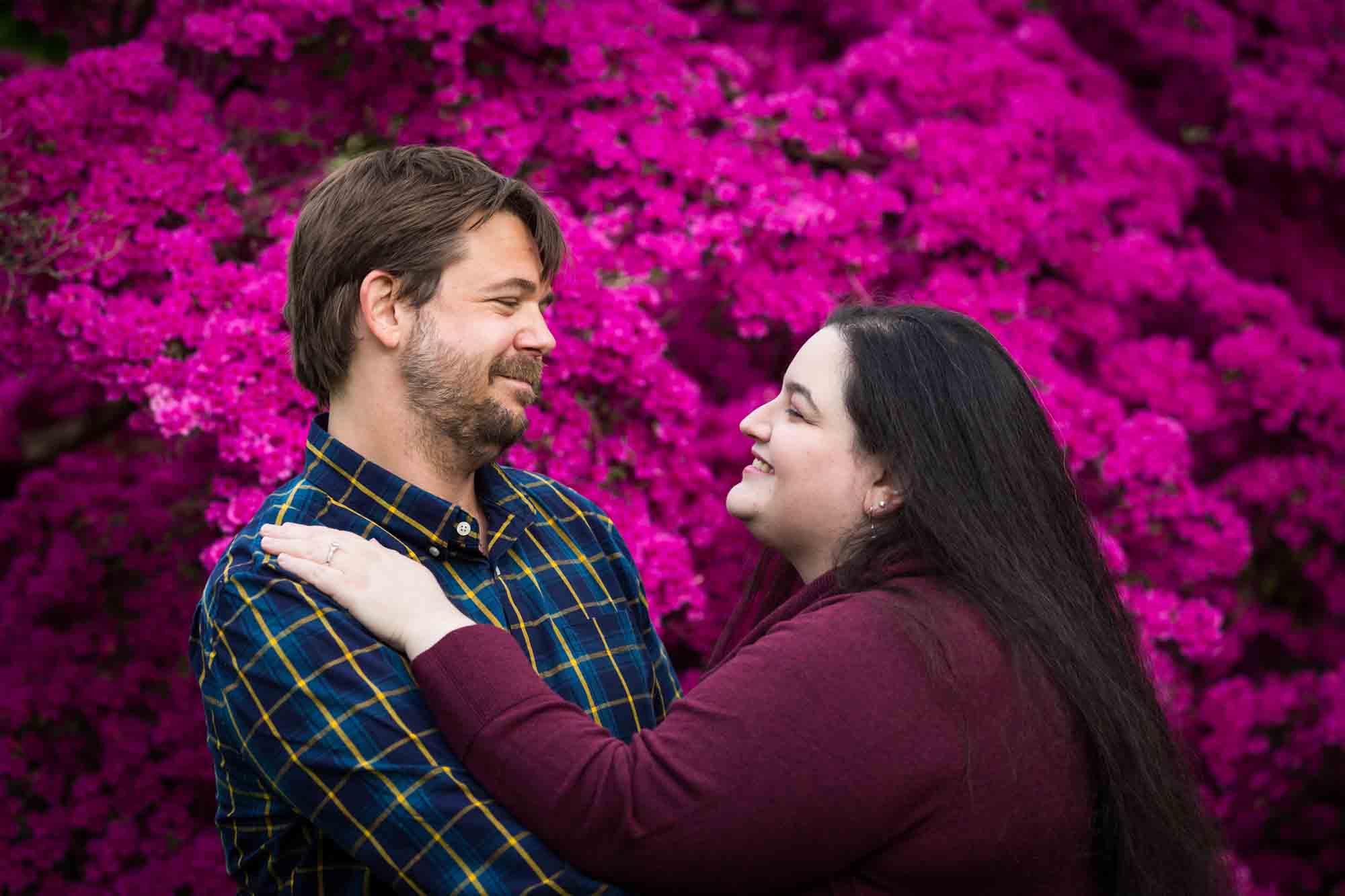 Snug Harbor engagement photos of couple hugging in front of pink azaleas