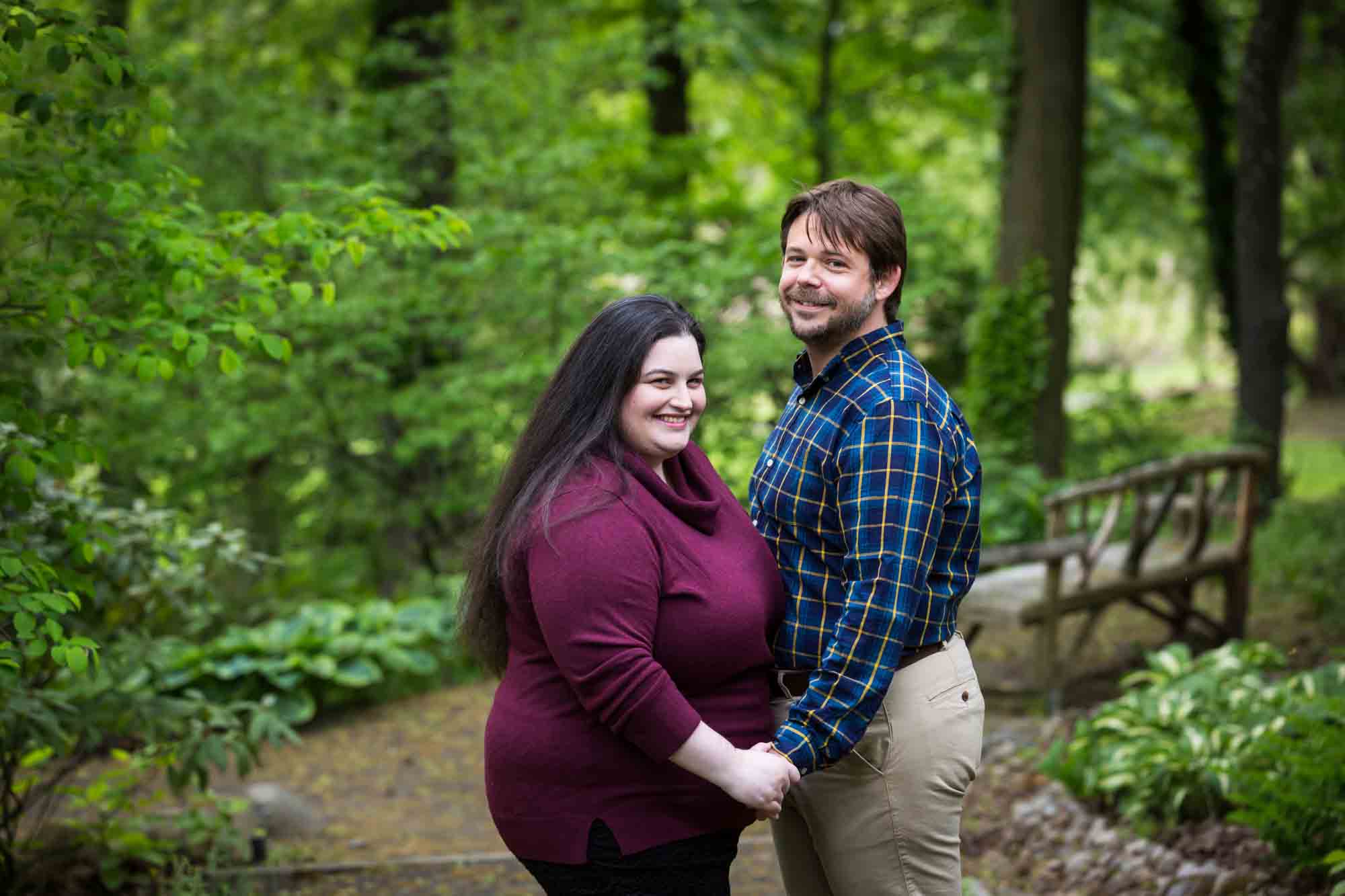 Snug Harbor engagement photos of couple holding hands in forest