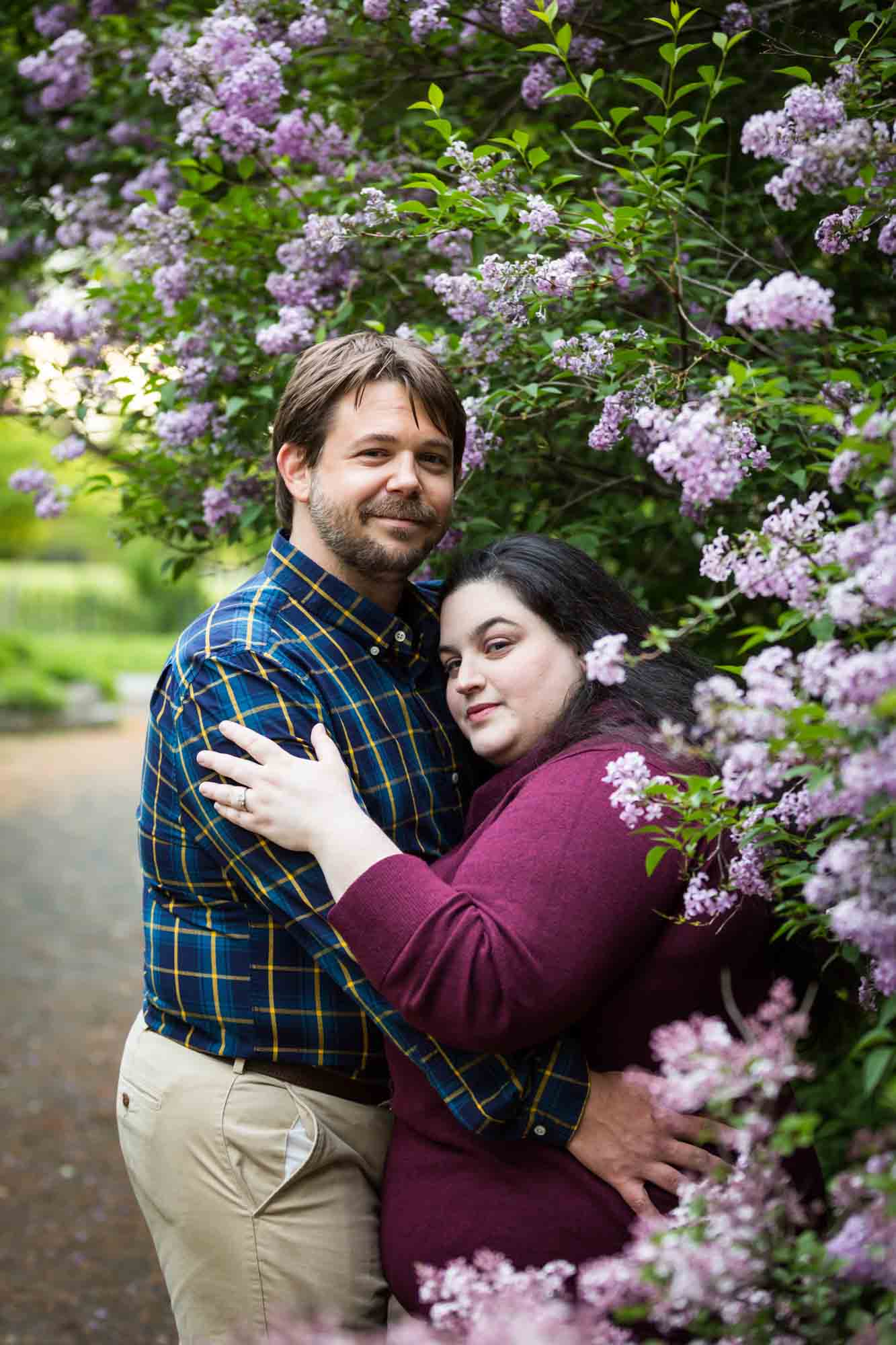 Couple hugging beside lilac bush in Snug Harbor