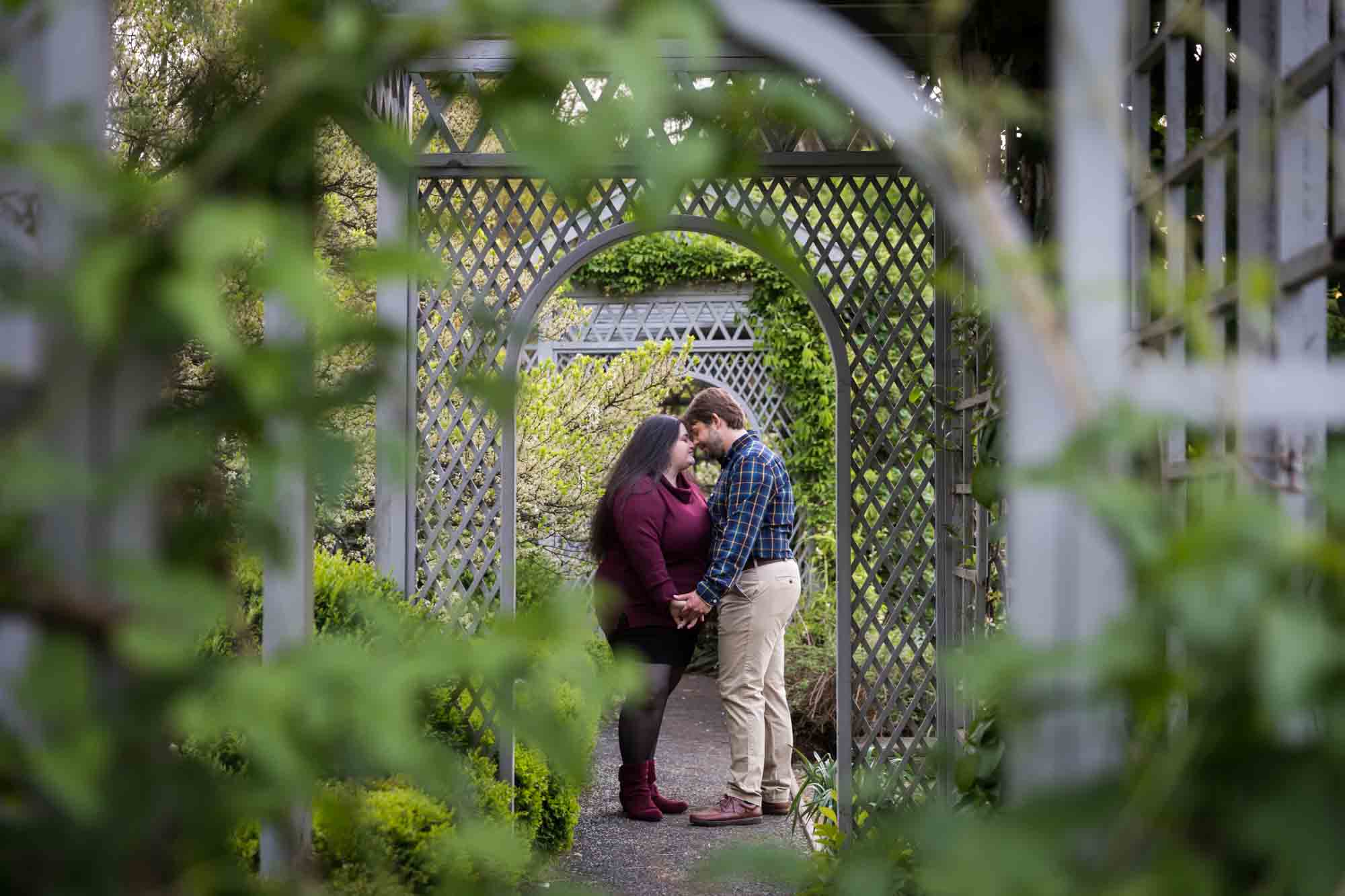 Snug Harbor engagement photos of couple hugging as seen through lattice