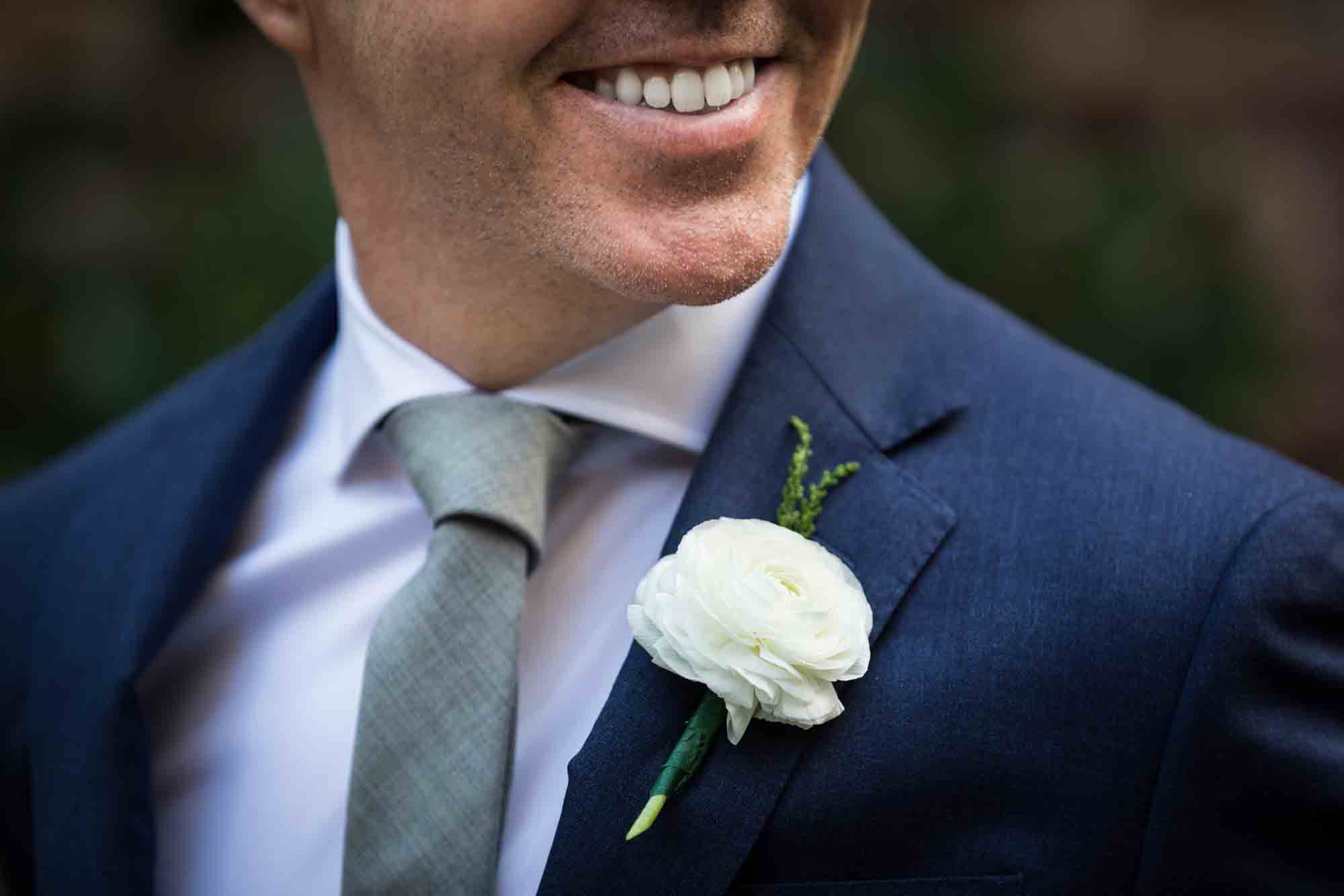Close up on smiling groom wearing white flower boutonnière
