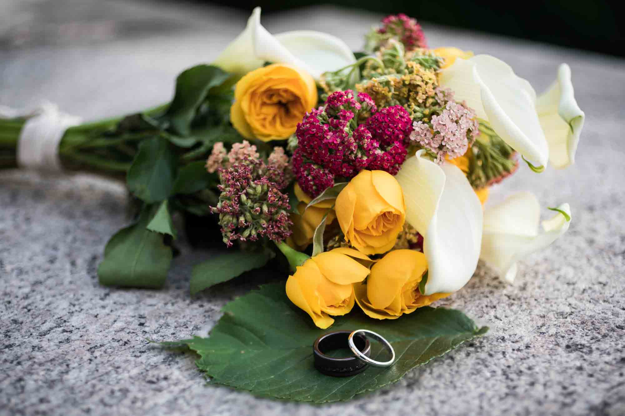 Yellow and white flower bouquet with wedding rings on leaves for article on wedding bouquet photo tips