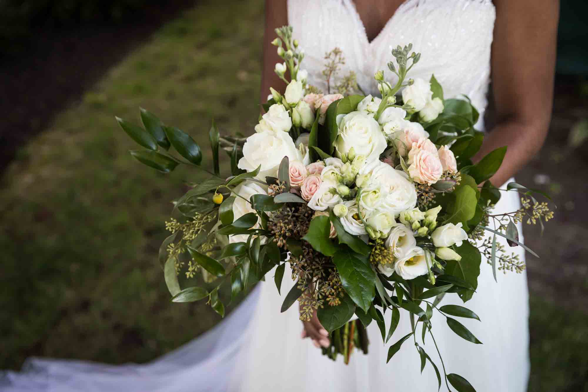 Close up of bride carrying a large white flower bouquet for article on wedding bouquet photo tips