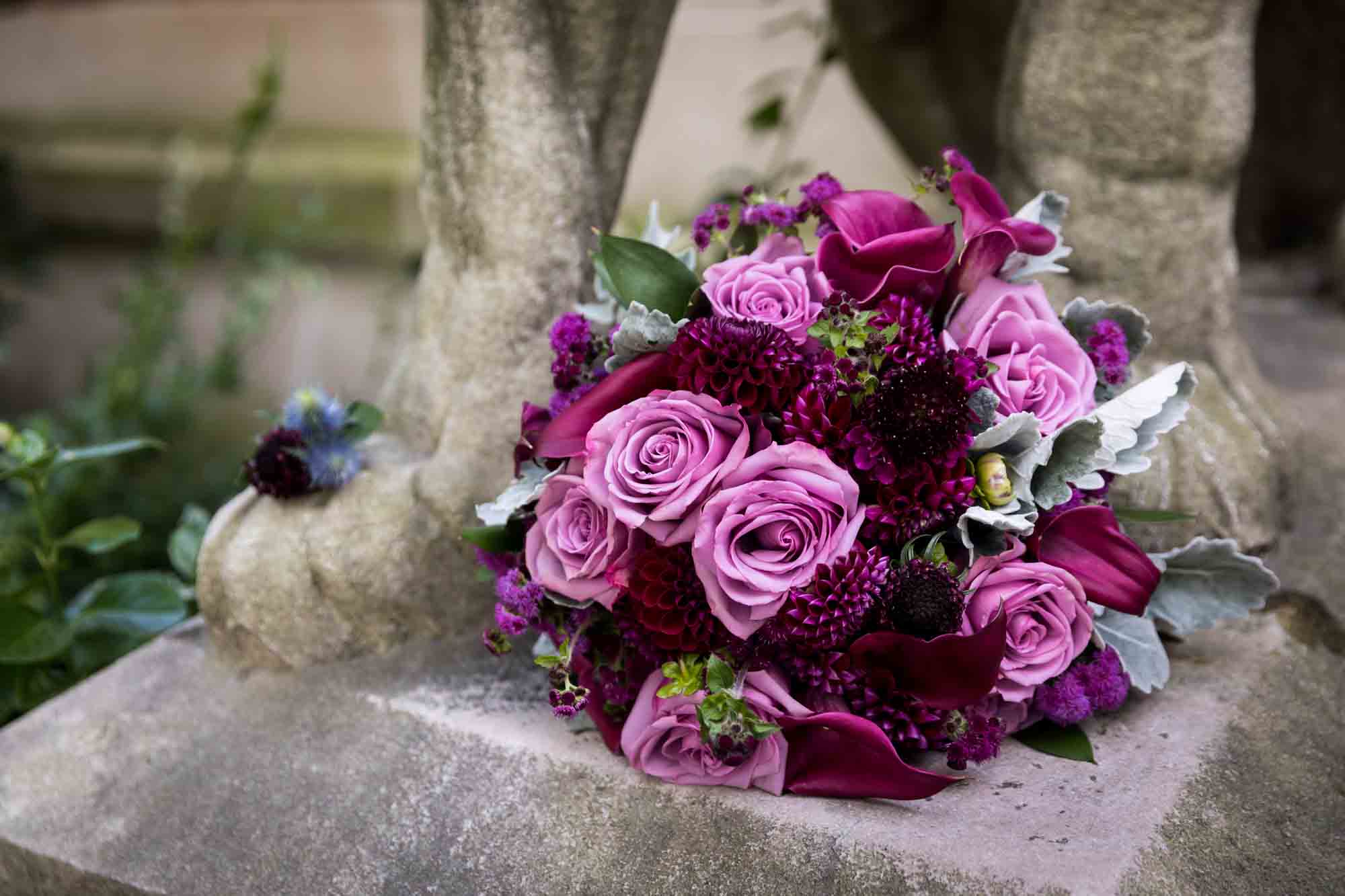 Close up of pink flower bouquet sitting on statue of lion's feet