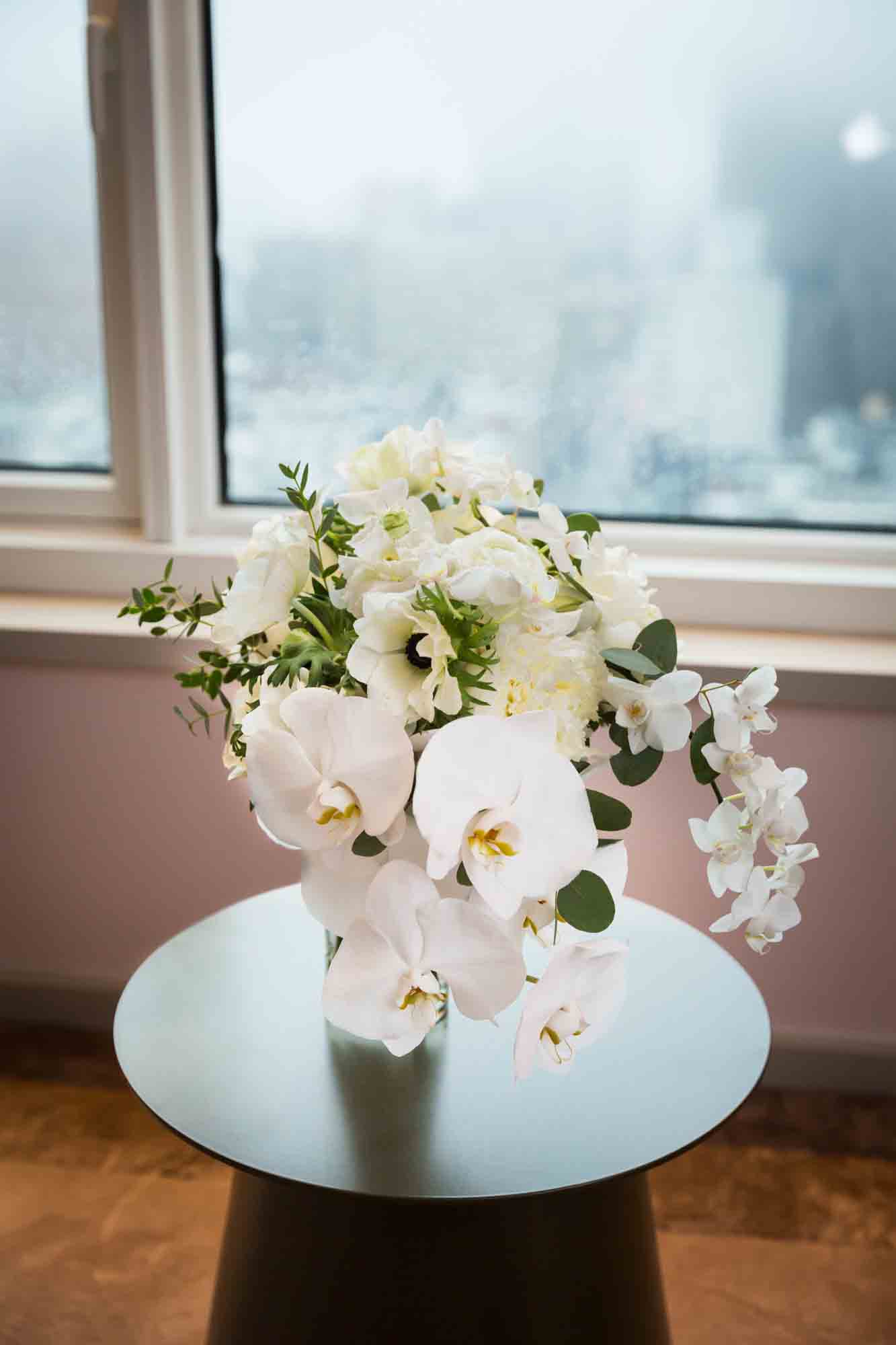 Bouquet of white flowers sitting on table in front of hotel window