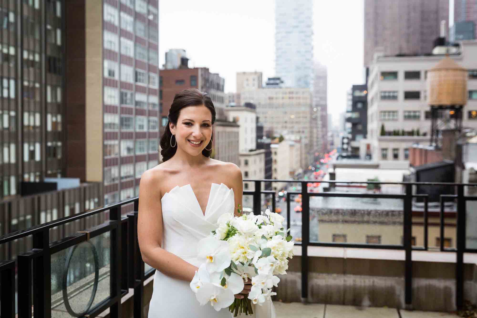 Bride holding white flower bouquet on NYC hotel rooftop