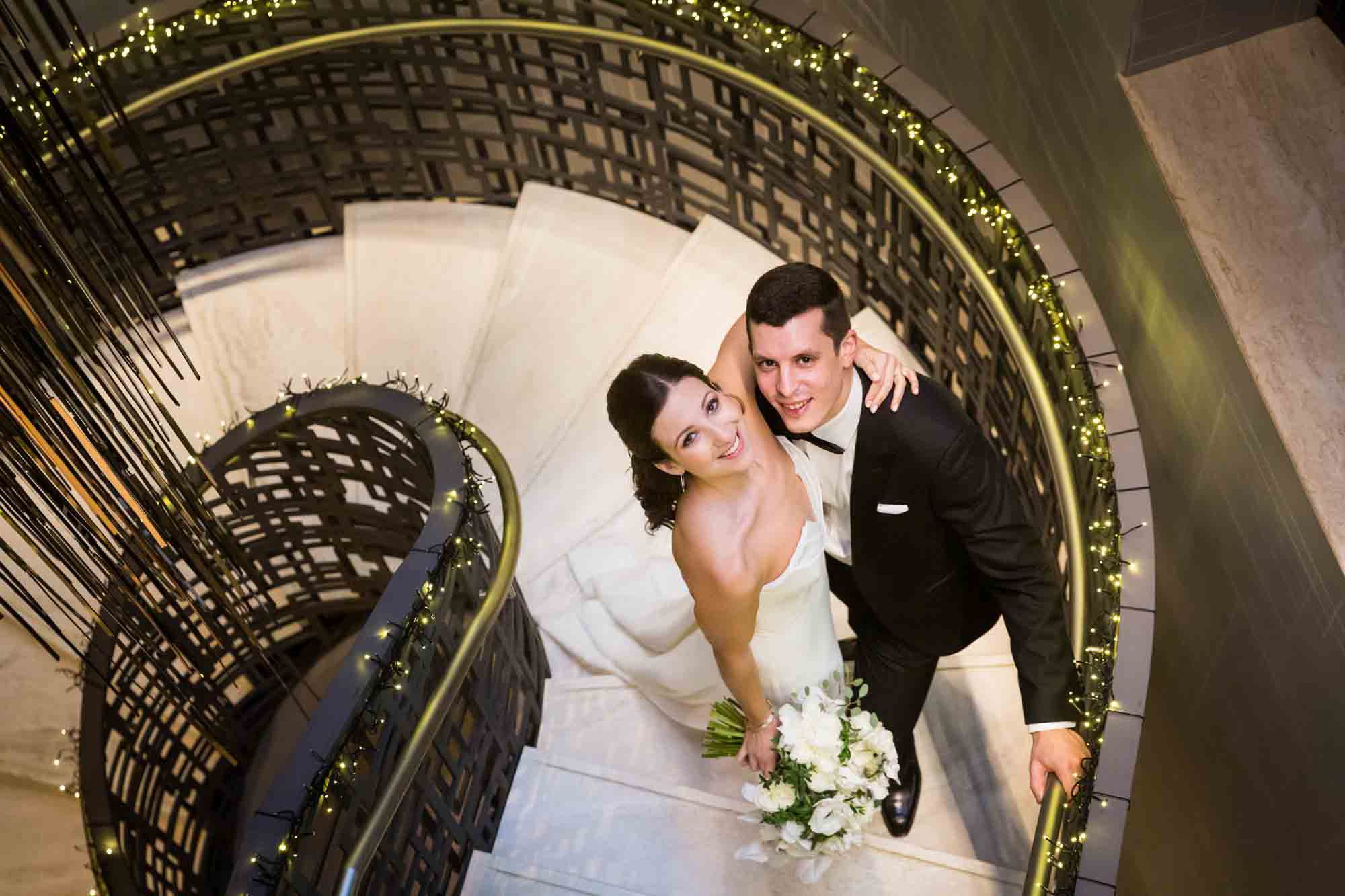 Bride and groom looking up from circular stairway for article on wedding bouquet photo tips