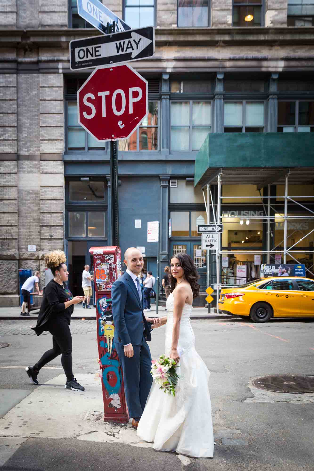 Bride and groom standing against stop sign on NYC street