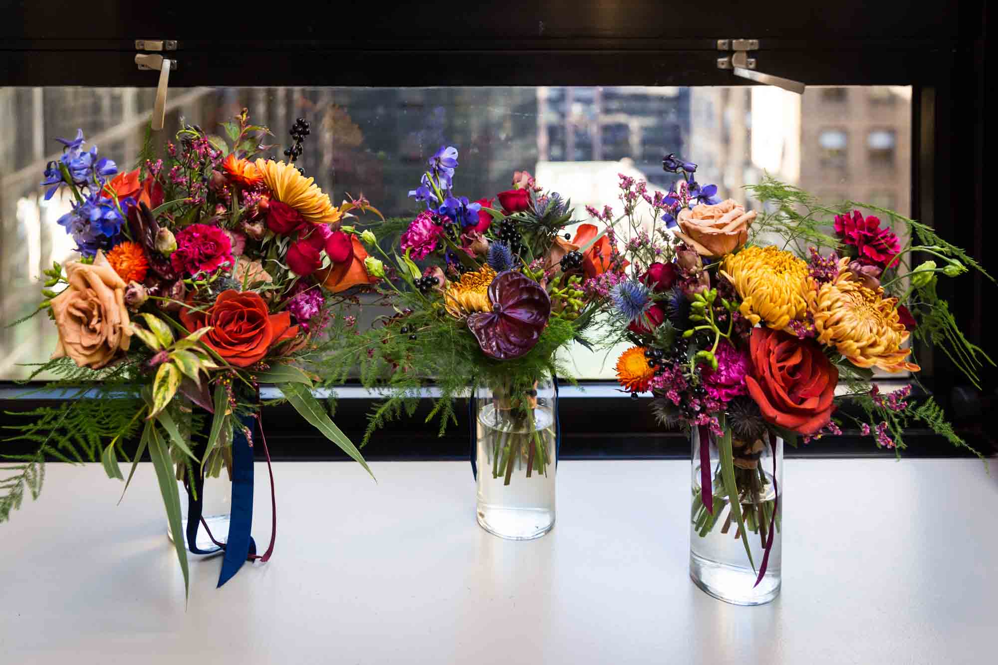 Three bouquets of colorful flowers on windowsill in NYC hotel room