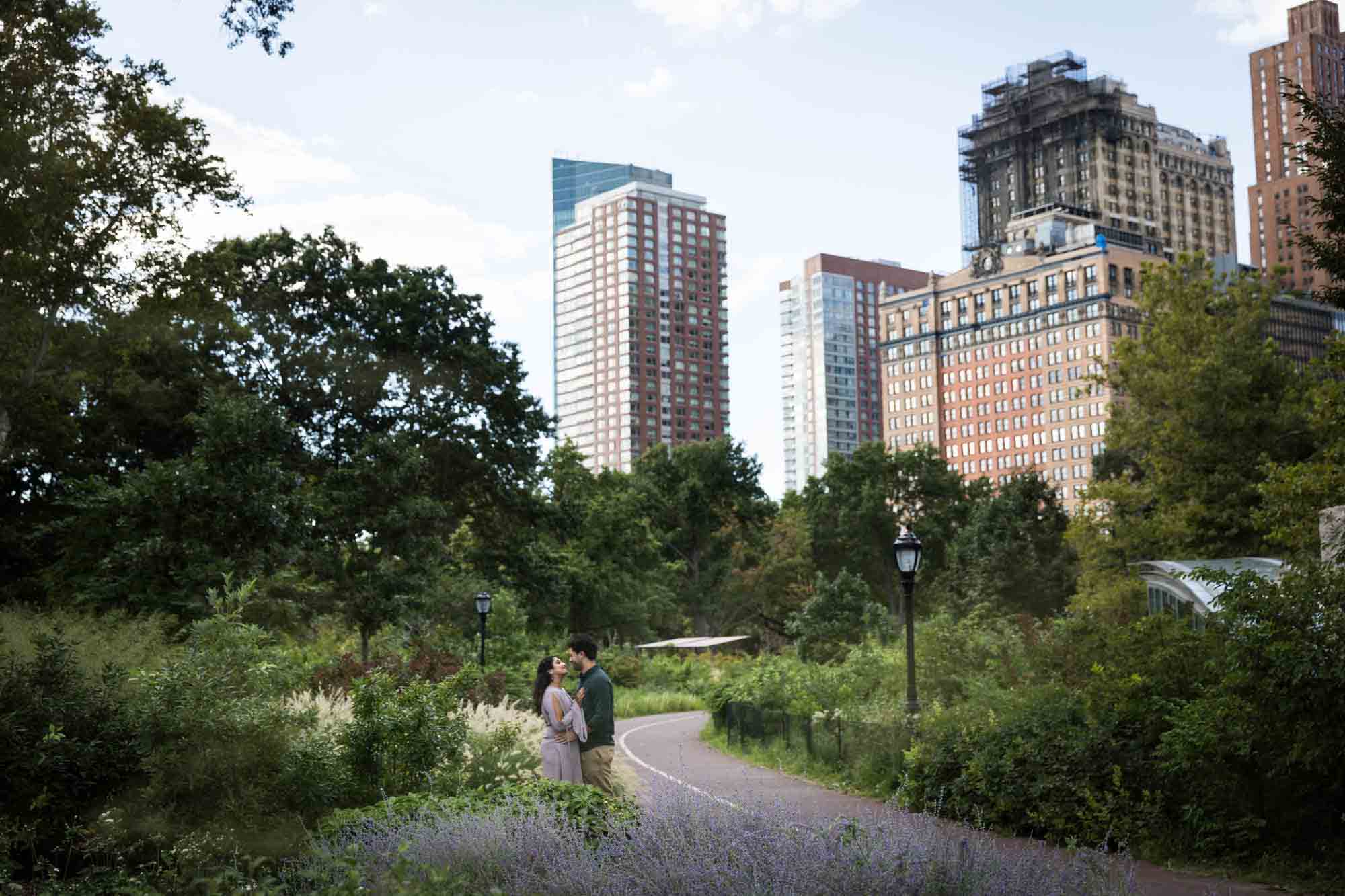 Battery Park engagement photos of couple in bike path with skyscrapers in background