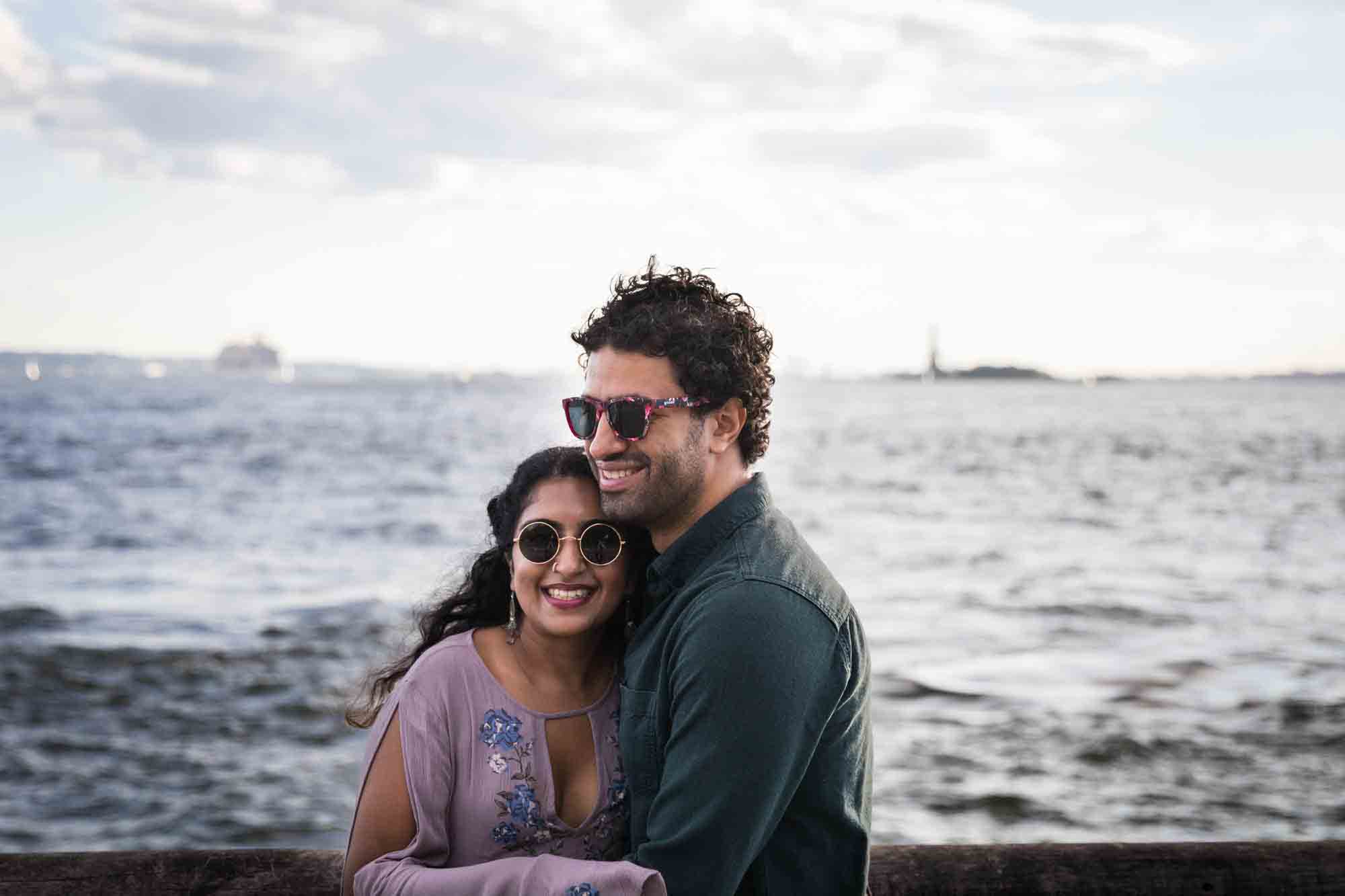 Battery Park engagement photos of couple hugging in front of NYC waterfront