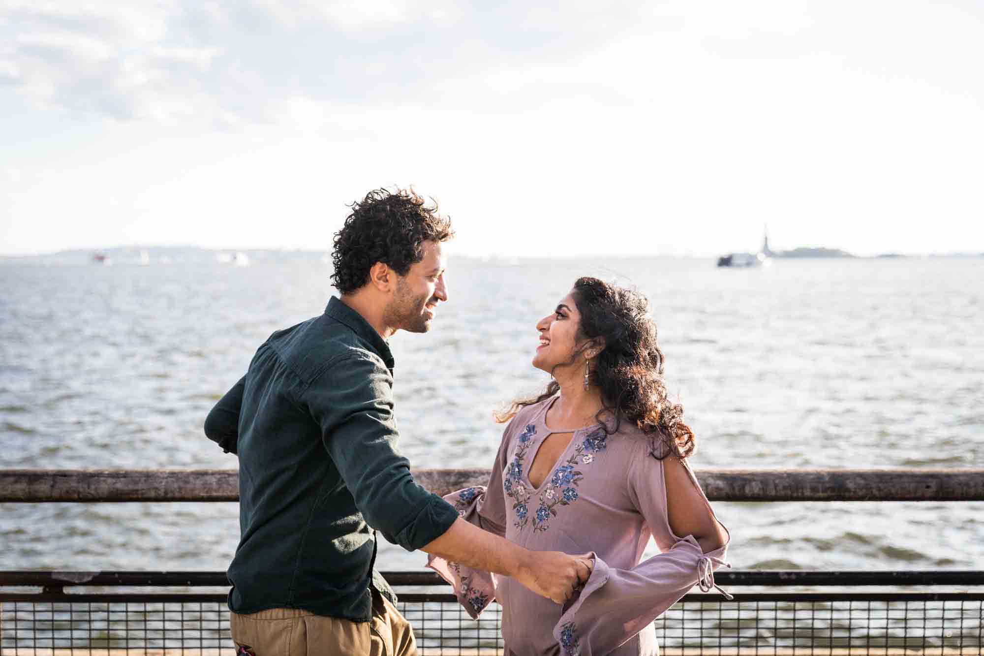 Battery Park engagement photos of couple dancing in front of NYC waterfront