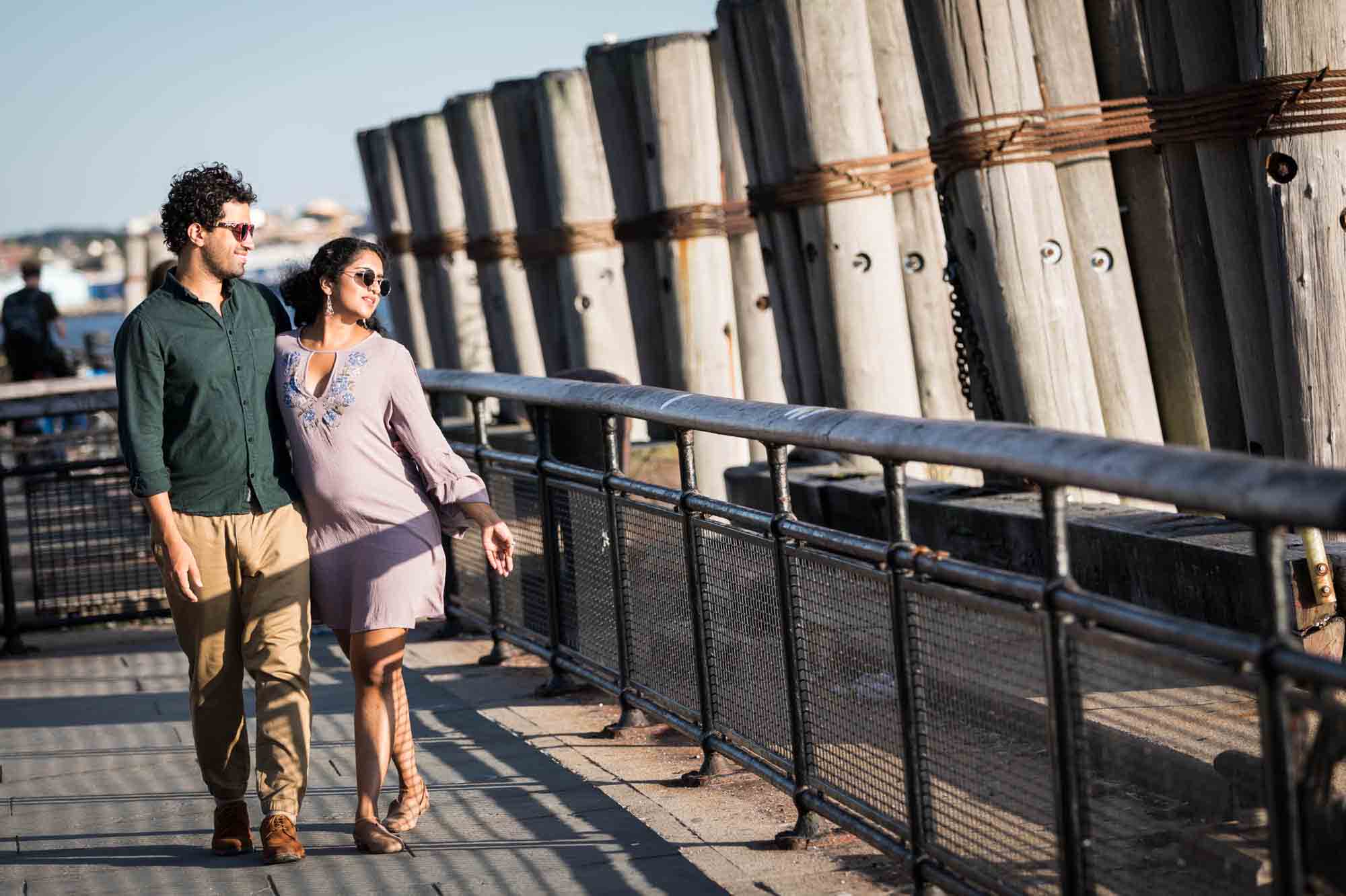 Battery Park engagement photos of couple walking in front of piers