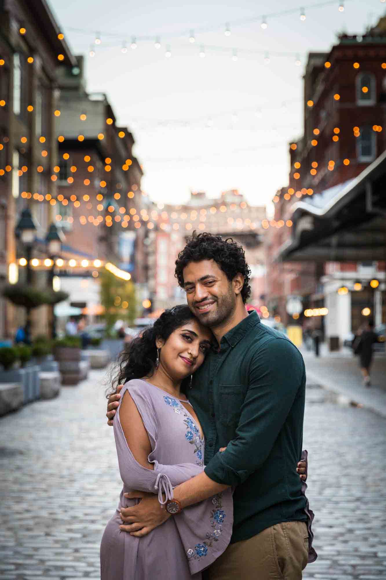 Couple hugging under fairy lights on Front Street in South Street Seaport