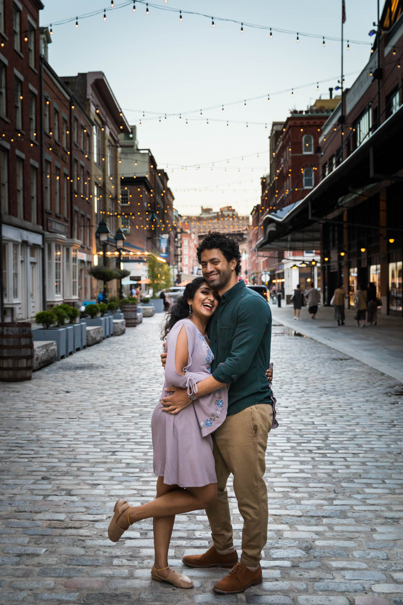 Couple hugging under fairy lights on Front Street in South Street Seaport