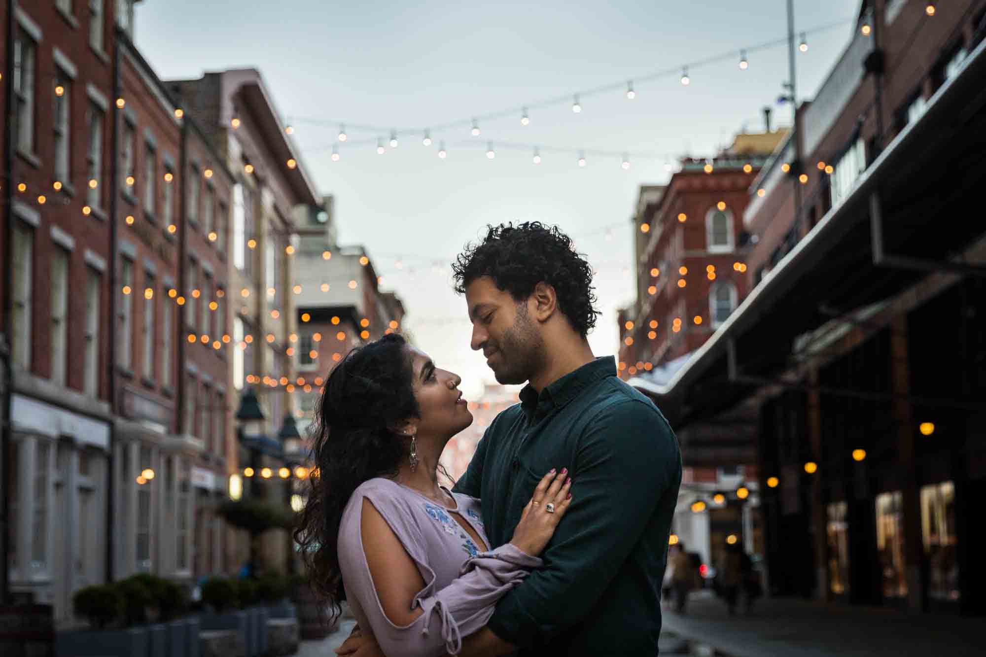 Couple hugging under fair lights at dusk in South Street Seaport