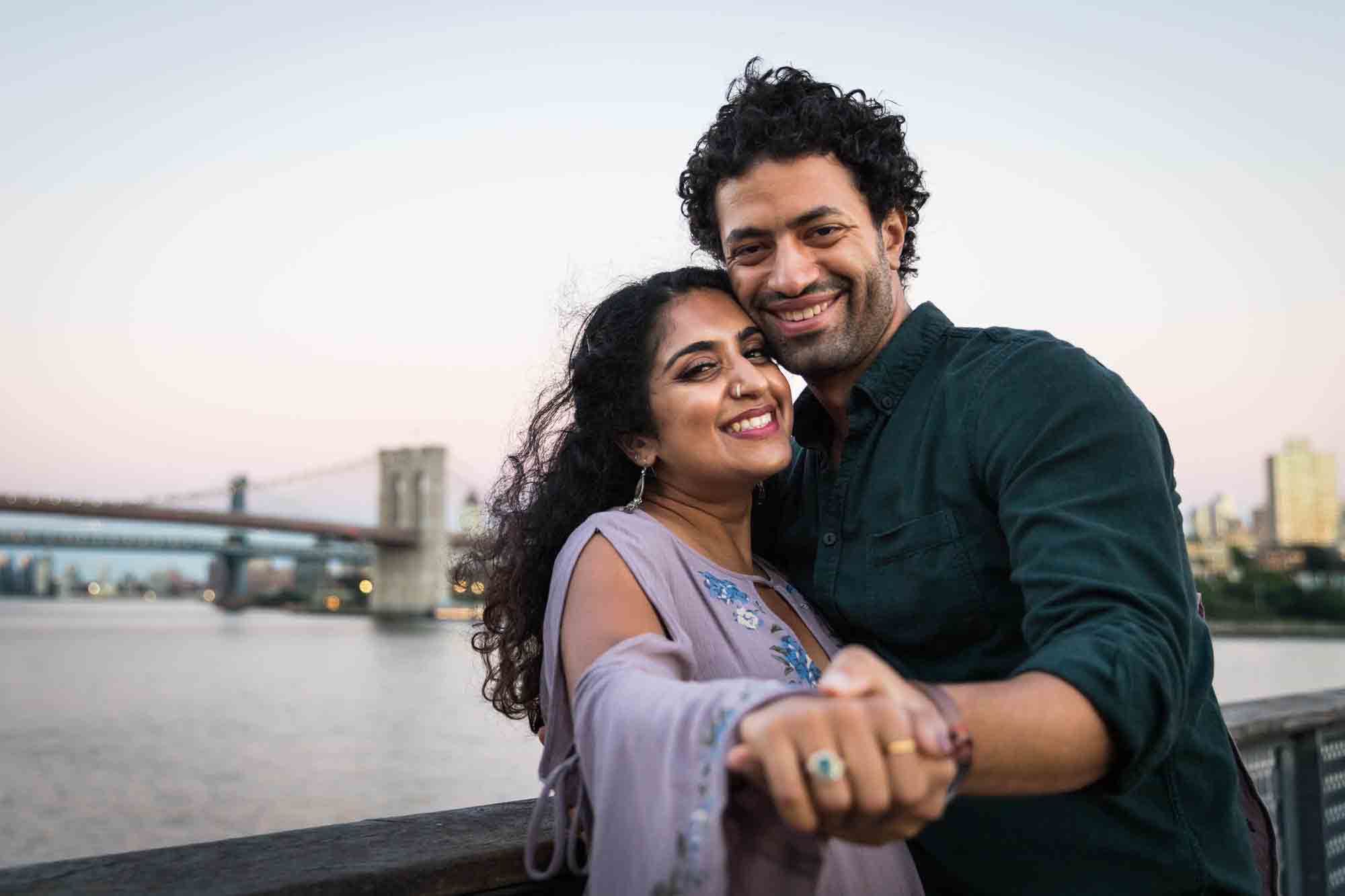 Couple with hands extended to camera to show off engagement ring