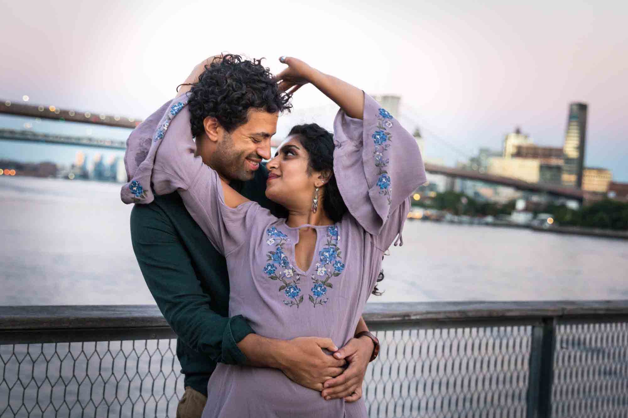 Couple dancing on Pier 17 with Brooklyn Bridge at sunset in background