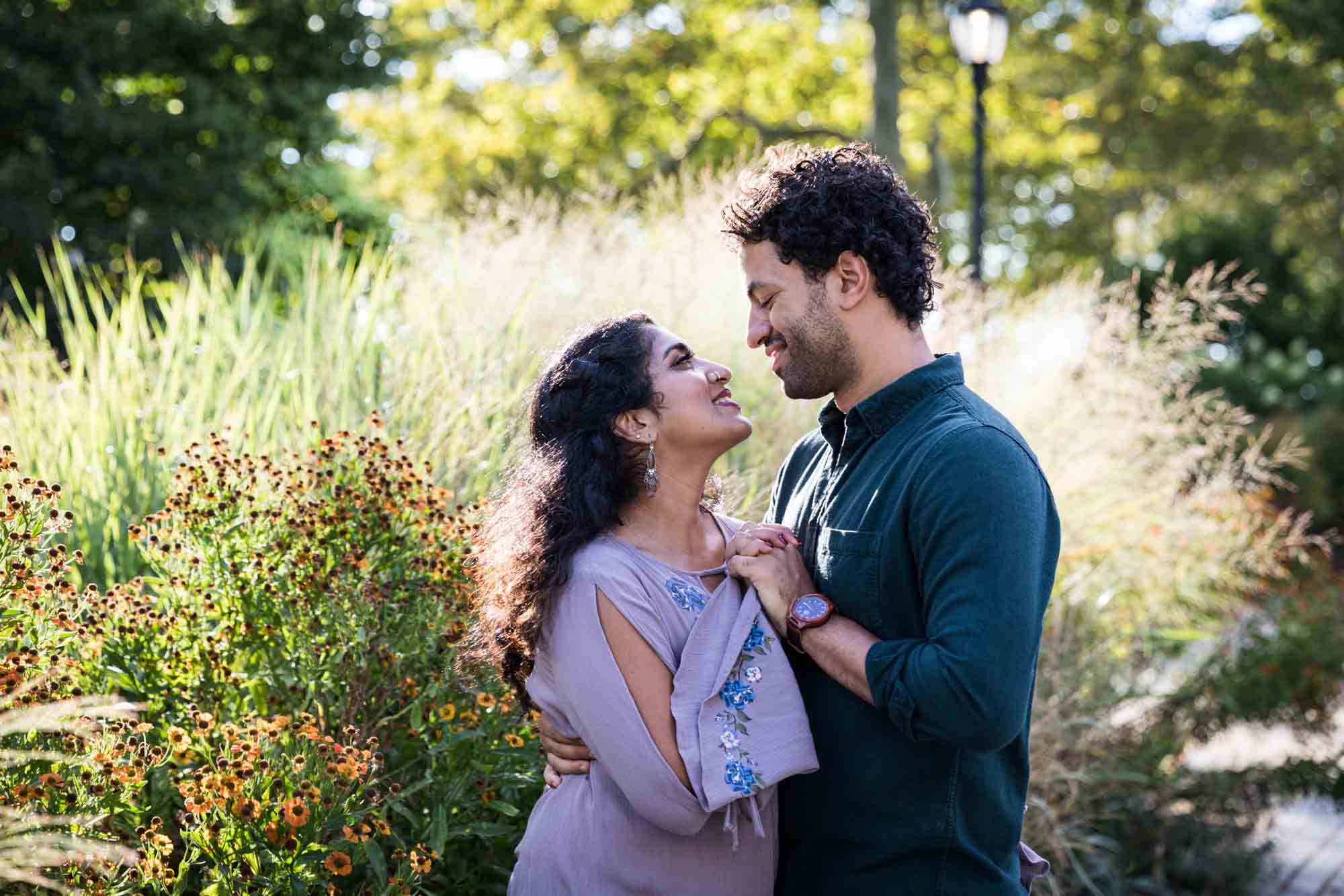 Battery Park engagement photos of couple holding hands in front of tall grass