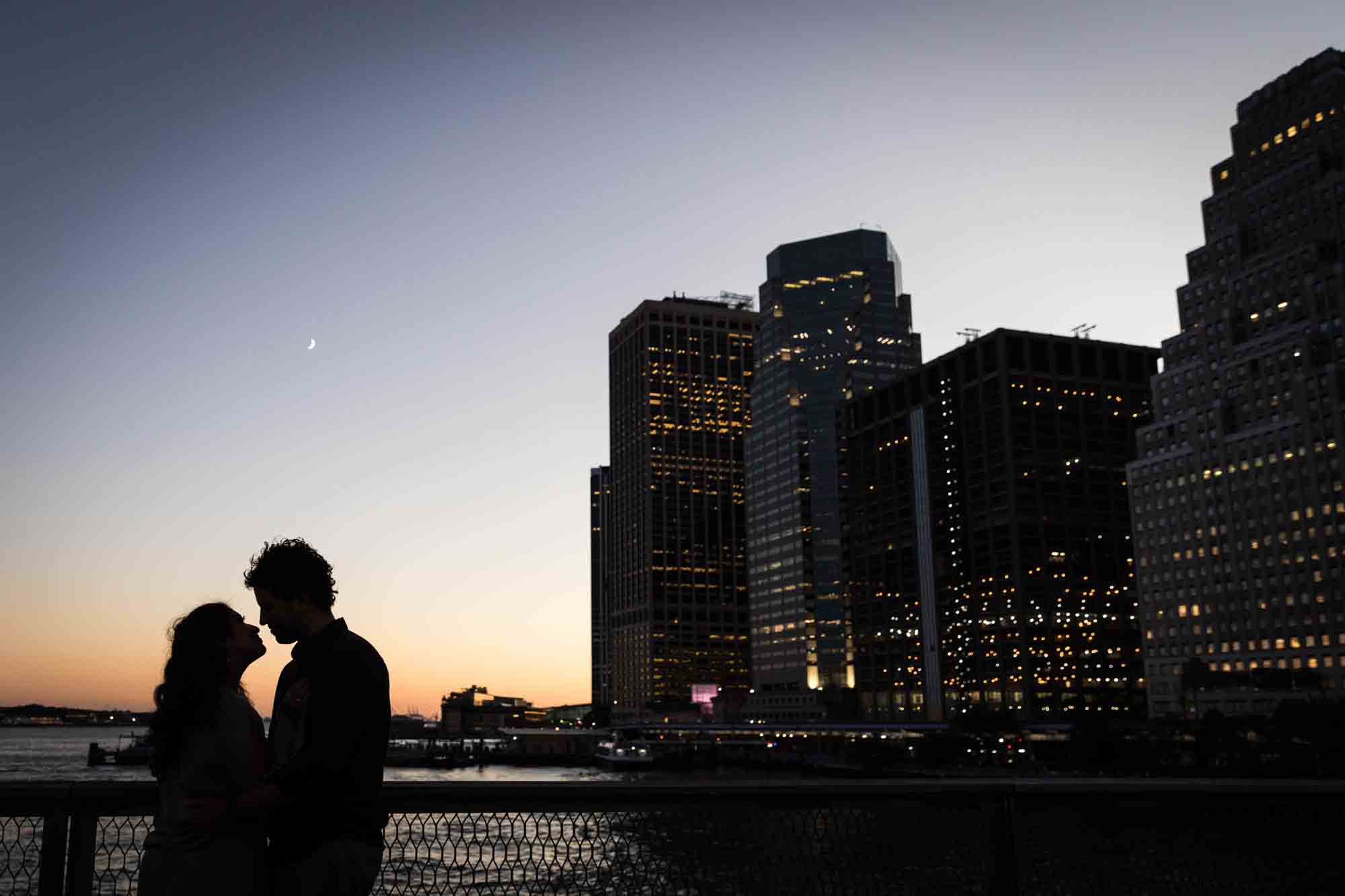 Backlit photo of couple and Manhattan skyline along waterfront