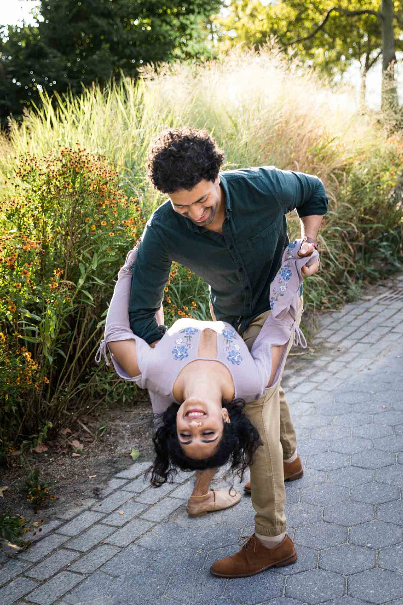 Battery Park engagement photos of man dipping woman in front of tall grass