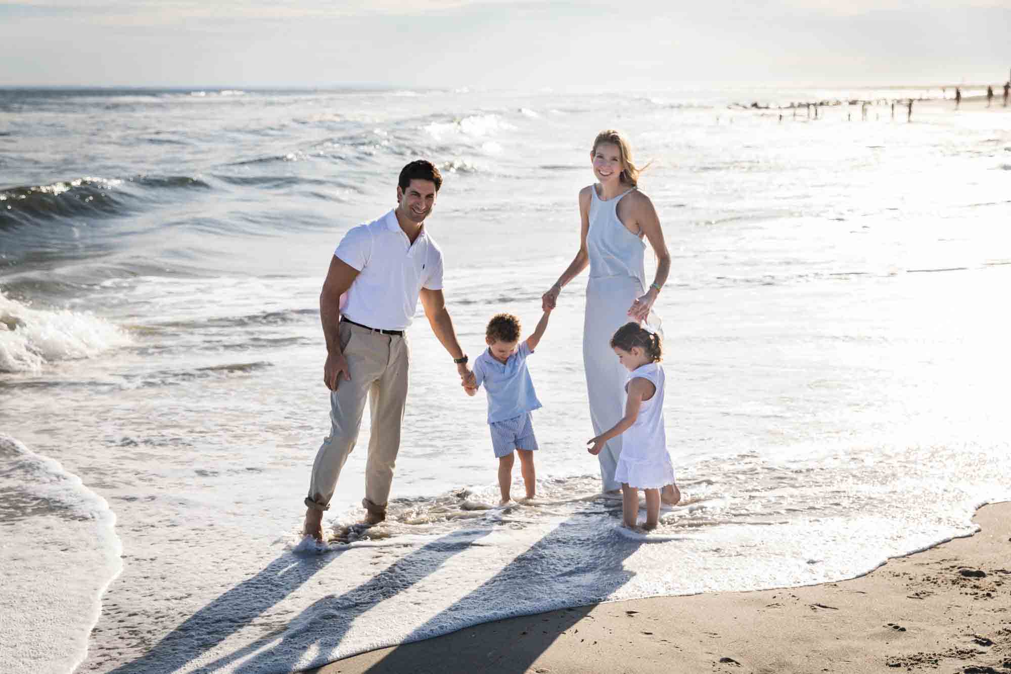 Fort Tilden beach family portrait of family with two kids walking along the ocean shore