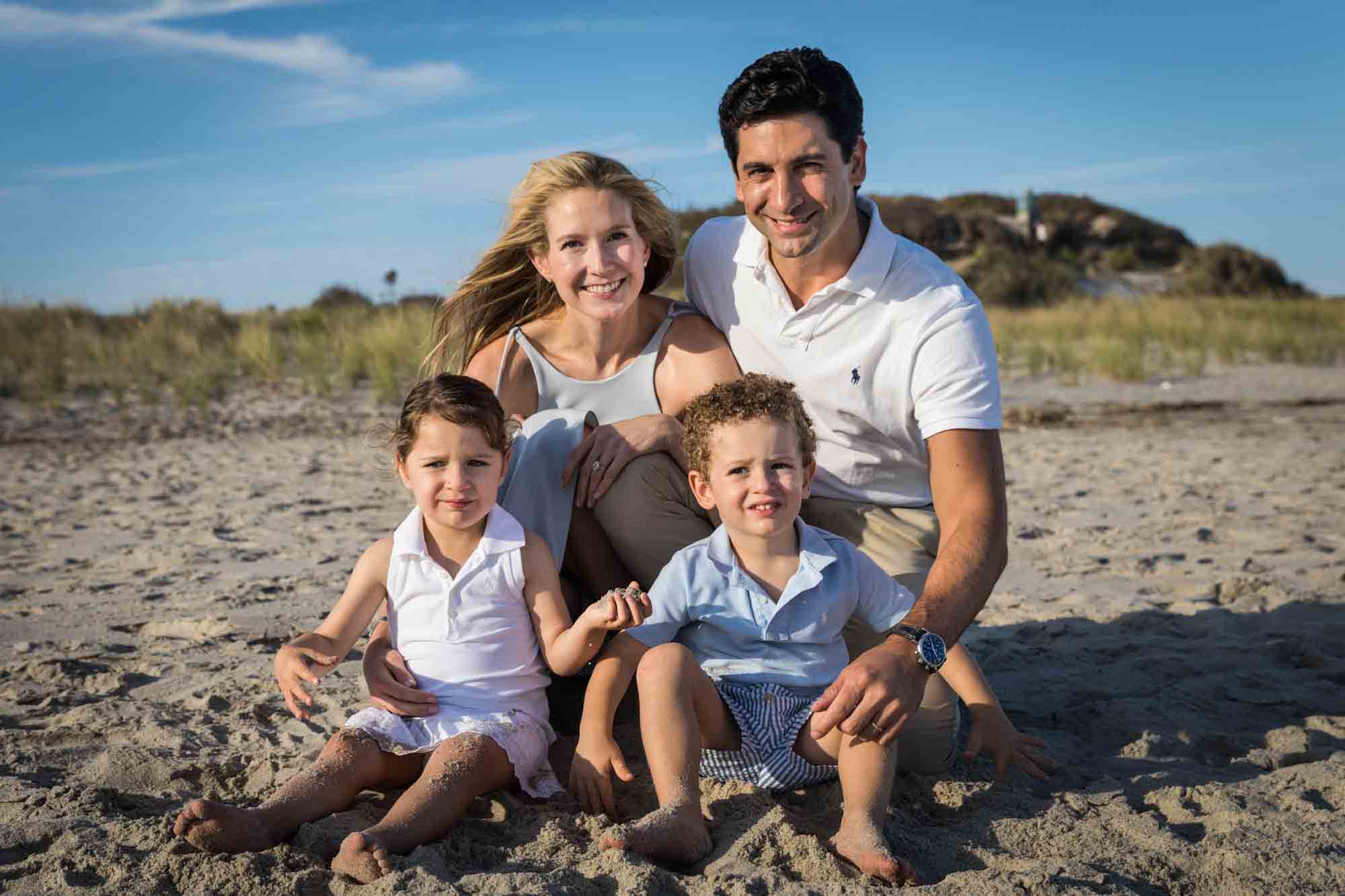 Fort Tilden beach family portrait of a family with two kids sitting on a beach