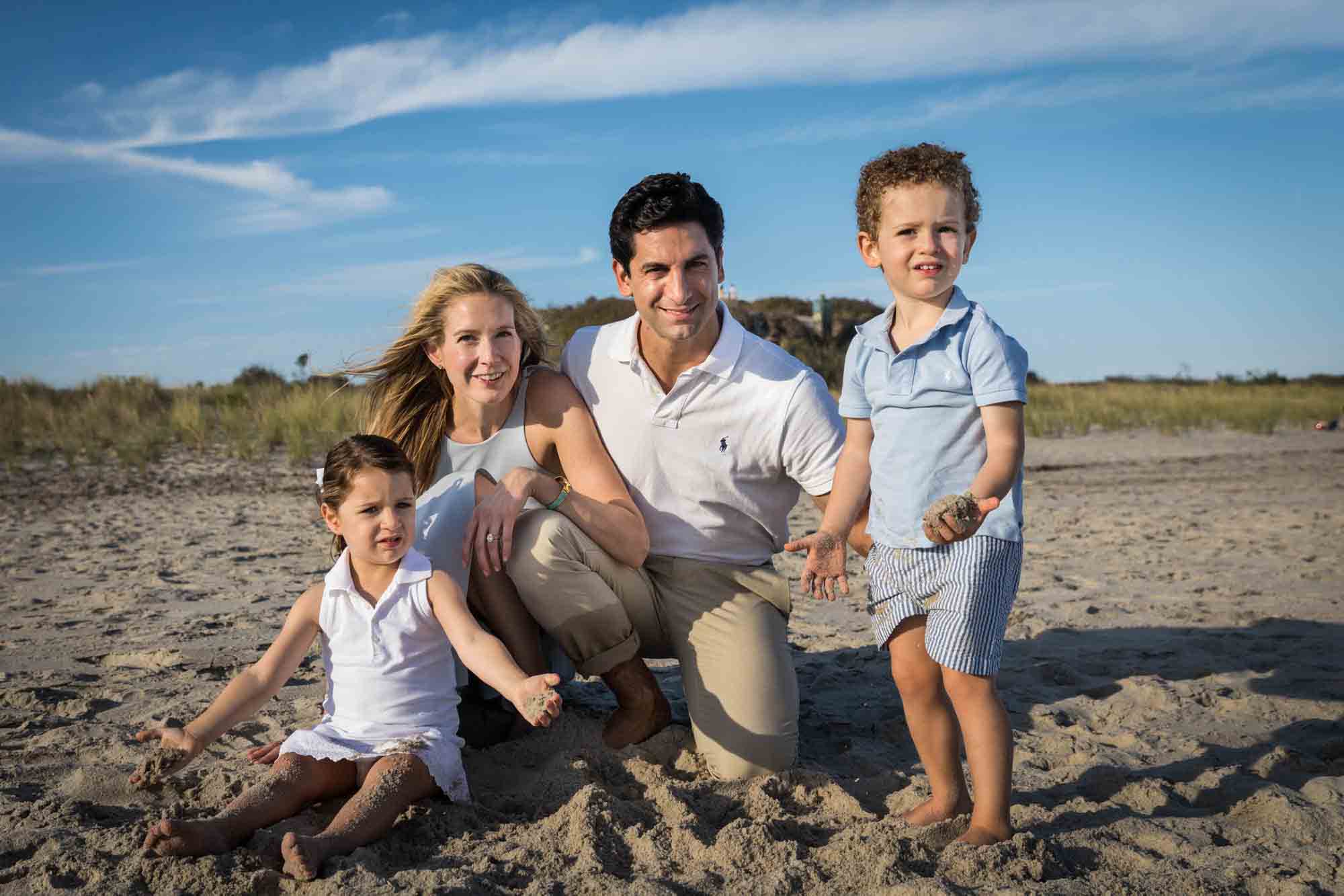 Fort Tilden beach family portrait of a family with two kids sitting on a beach