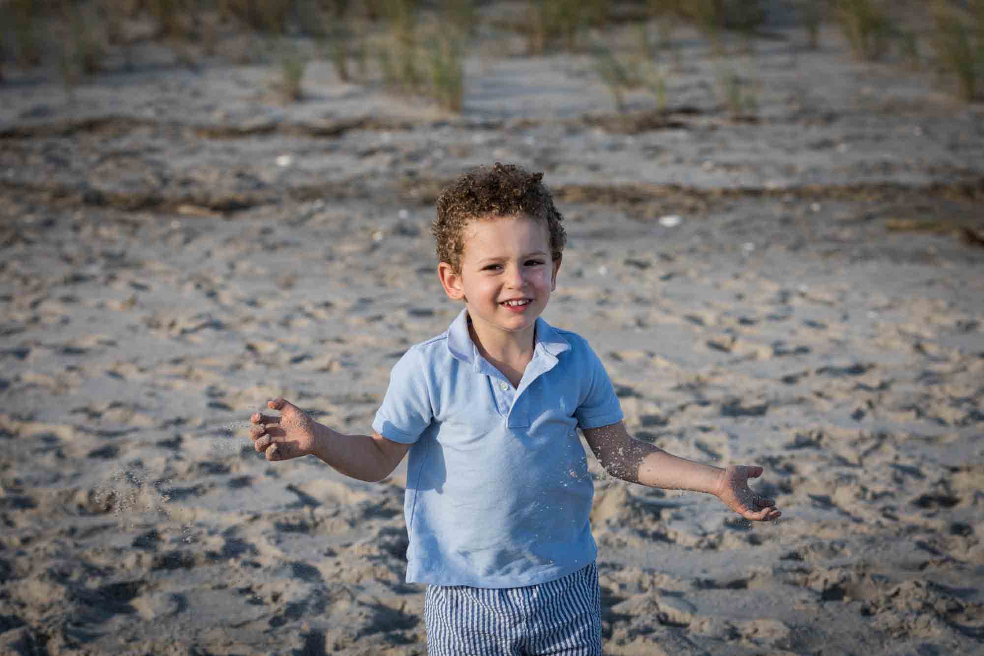 Fort Tilden beach family portrait of little boy with hands in air on the beach