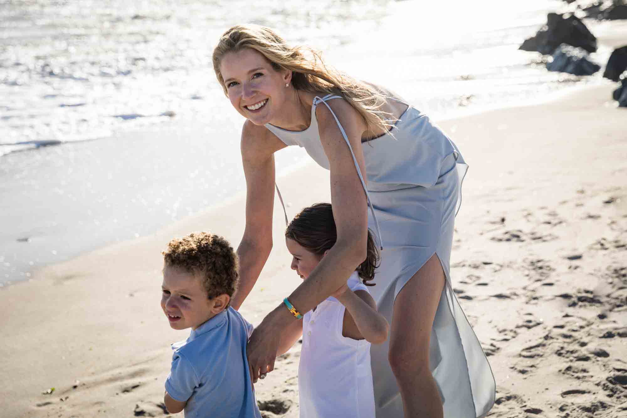 Mother with two small children on beach in front of ocean for an article on beach family portrait tips