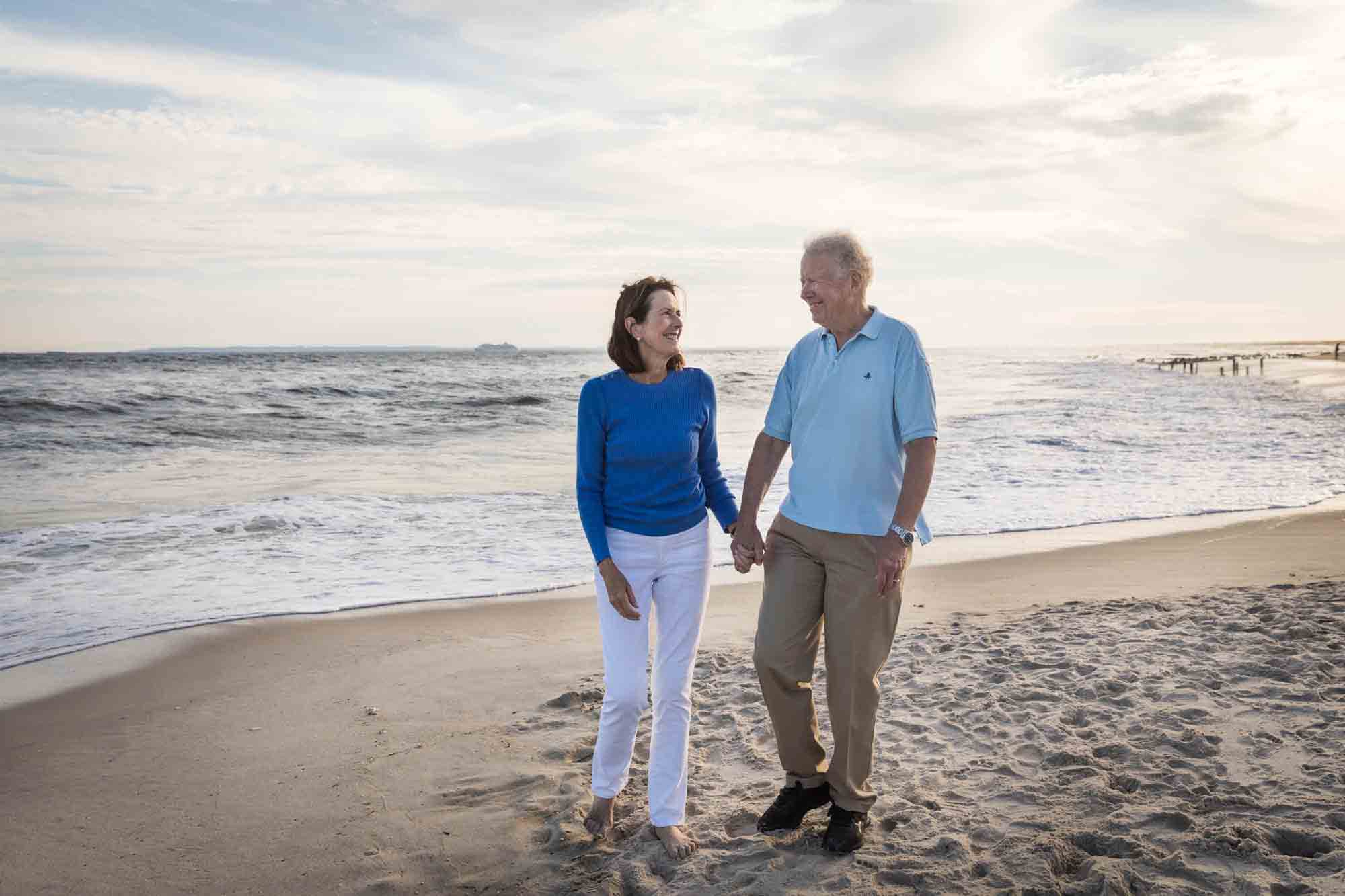 Beach family portrait of grandparents holding hands in front of ocean