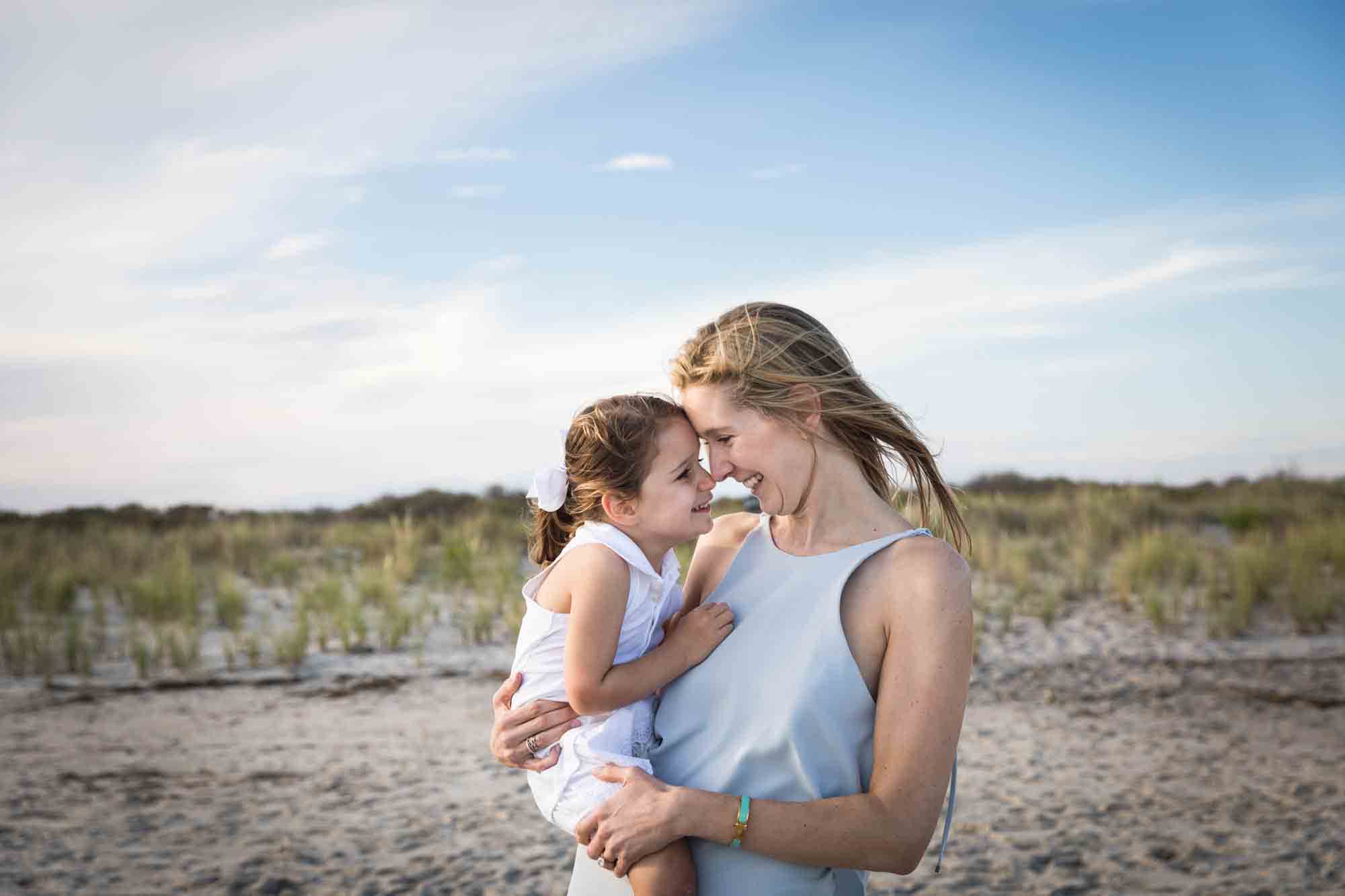 Beach family portrait of mother holding small girl in front of sand dunes