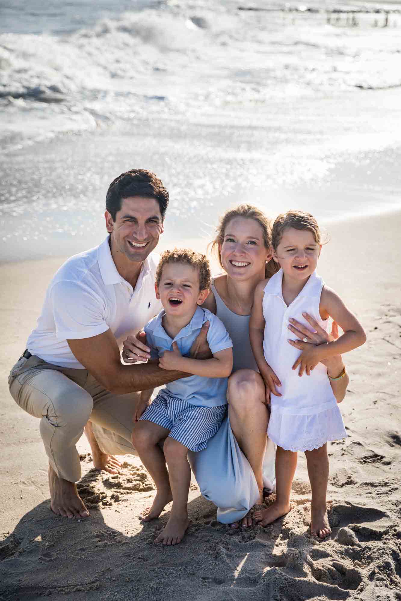 Parents with two small children on beach in front of ocean for an article on beach family portrait tips