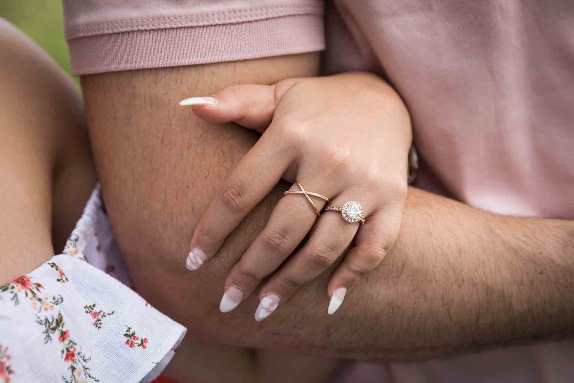 Woman's hand on man's arm showing rose gold engagement ring