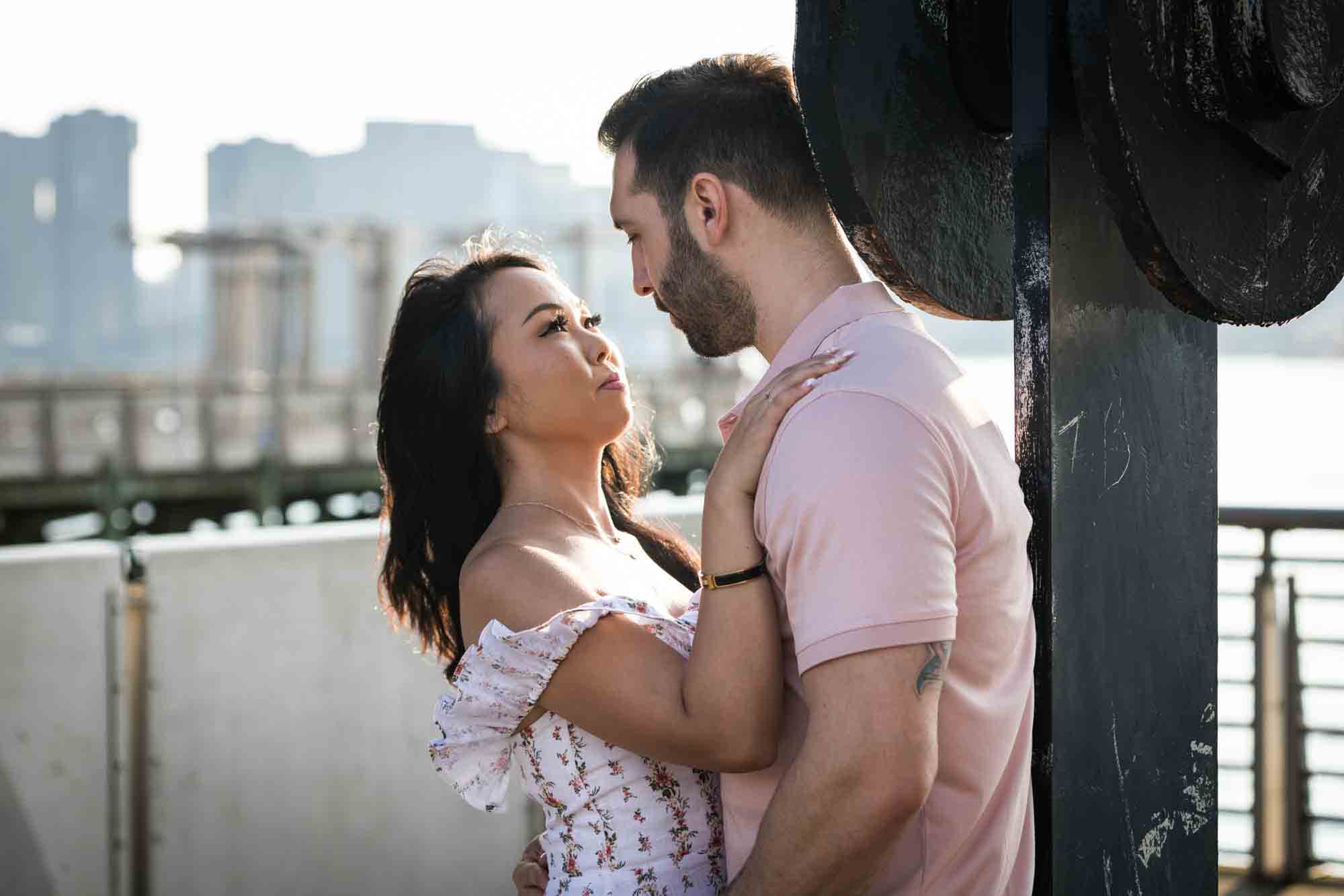 Couple hugging up against gantry during a Gantry Plaza State Park engagement photo shoot