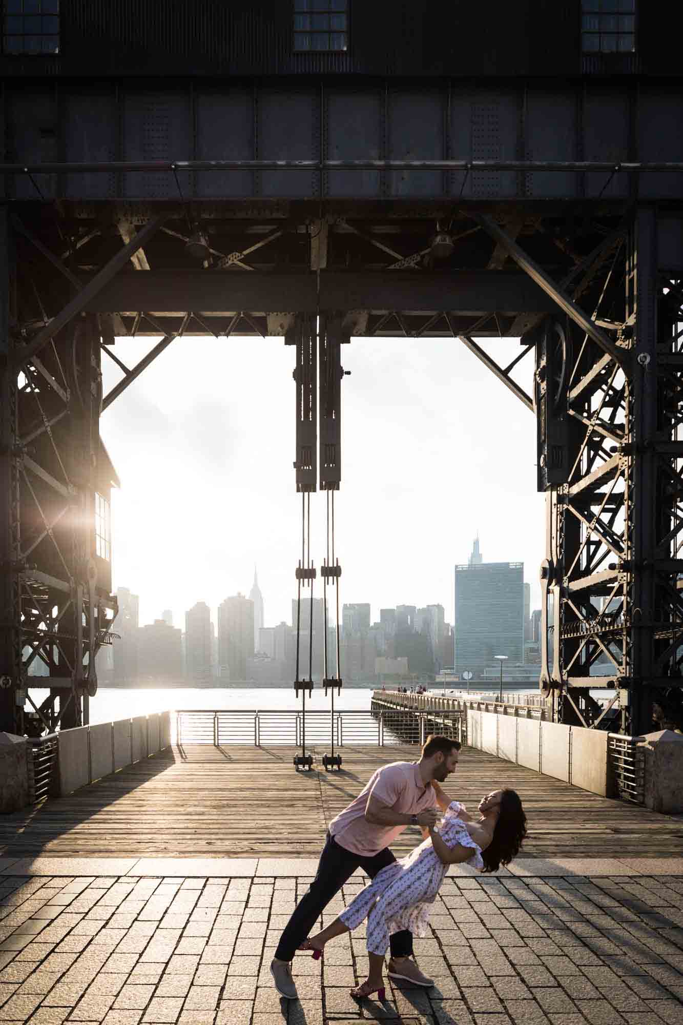 Couple dancing under gantry at sunset during a Gantry Plaza State Park engagement photo shoot