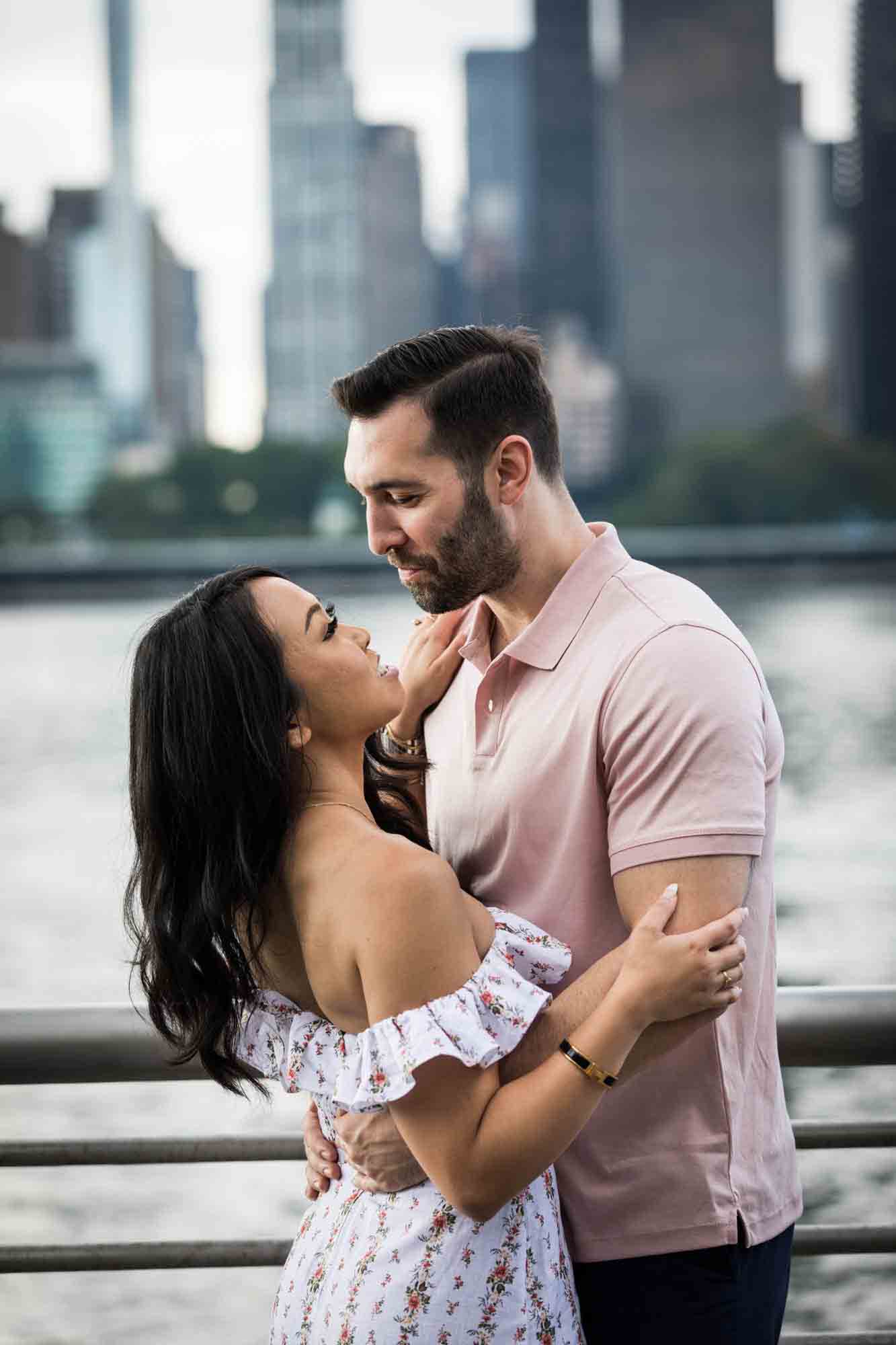 Couple hugging in front of NYC skyline during a Gantry Plaza State Park engagement photo shoot