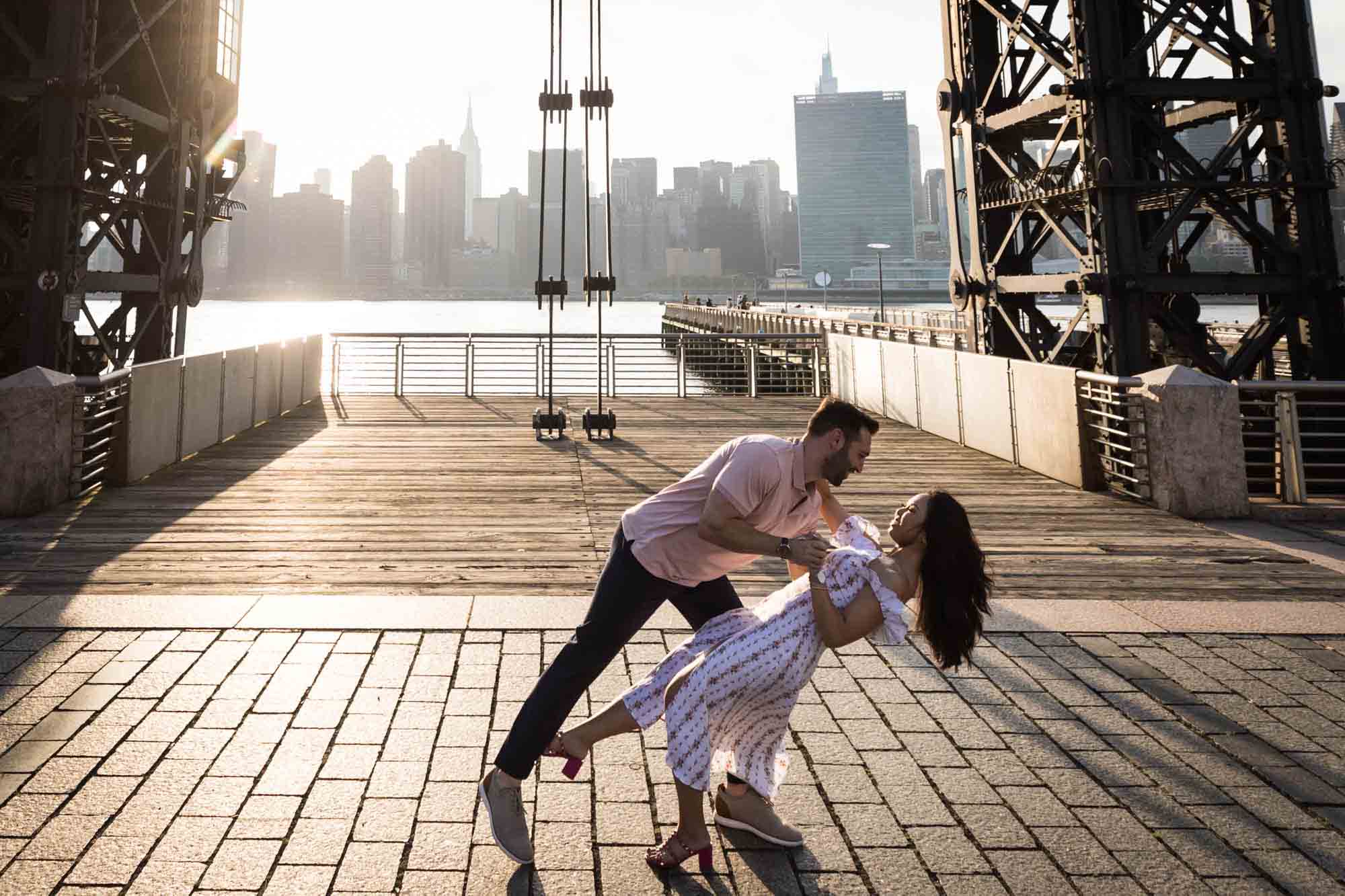 Couple dancing under gantry during Gantry Plaza State Park engagement session for an article on engagement portrait clothing tips