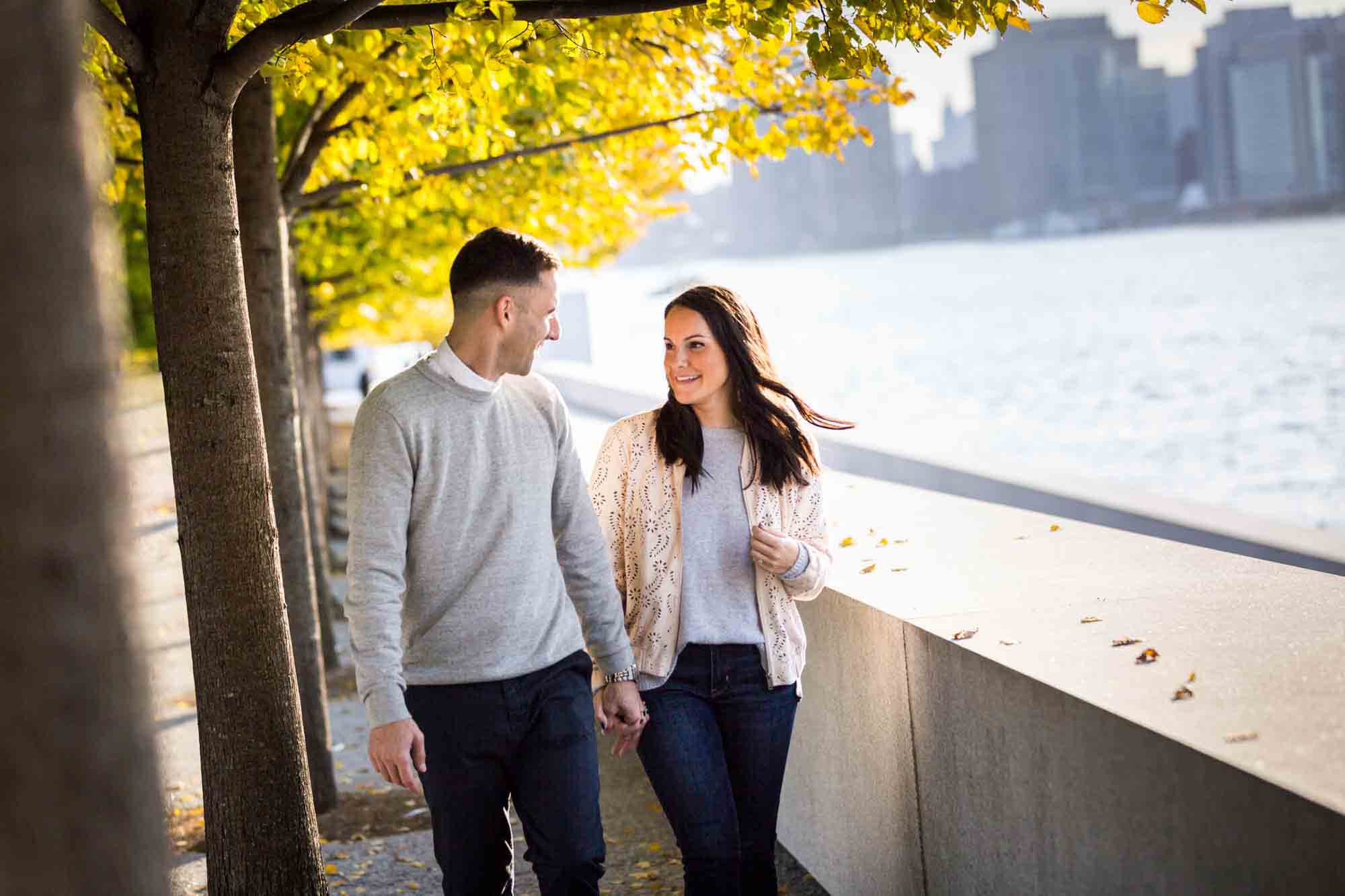 Couple under trees leaning against concrete railing during a Four Freedoms Park engagement photo shoot